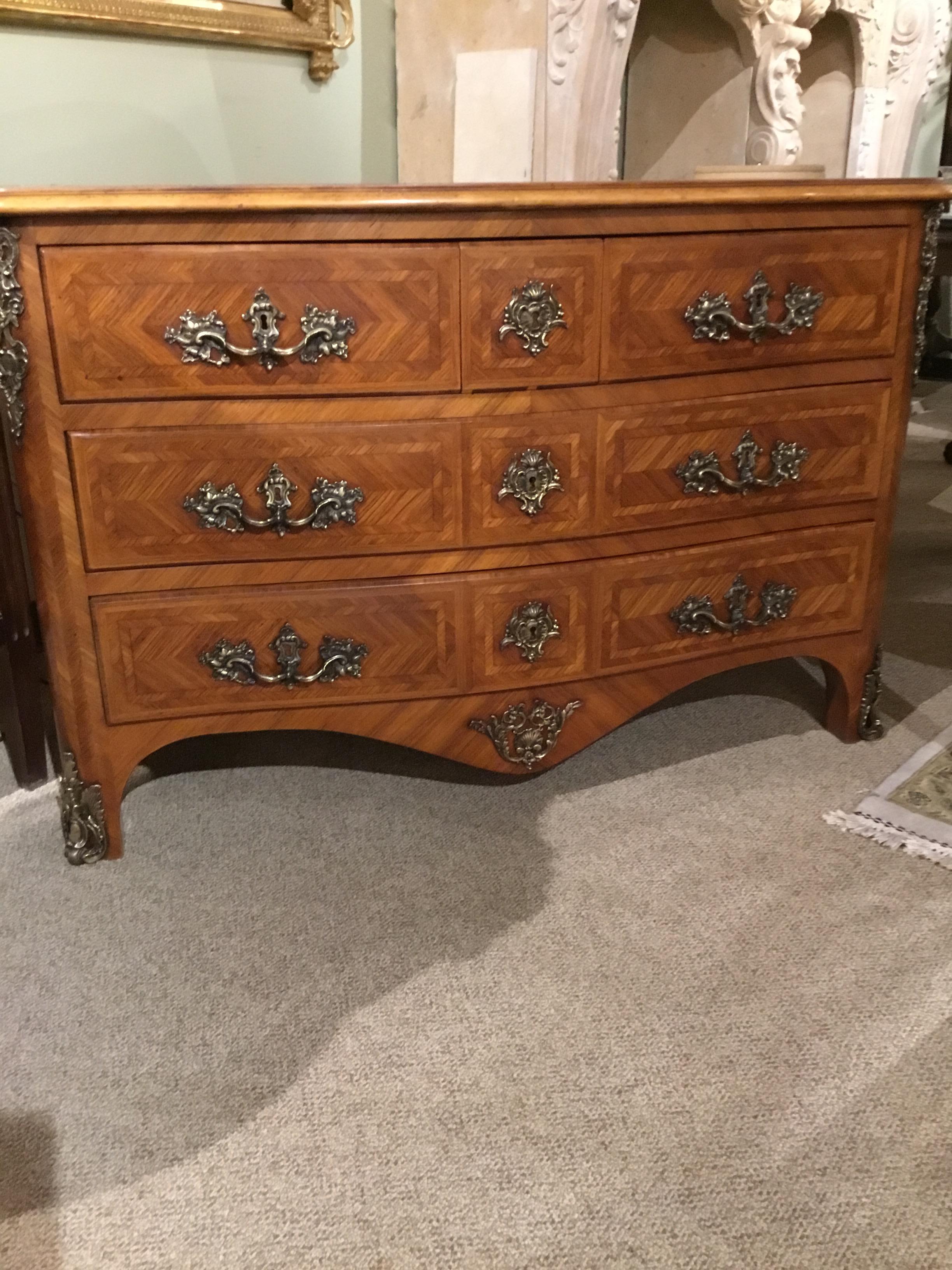 Handsome commode with bronze dore mounts. Three drawers that slide open easily and
Has deep drawers for great storage. Walnut marquetry that is inlaid in geometric patterns.
  