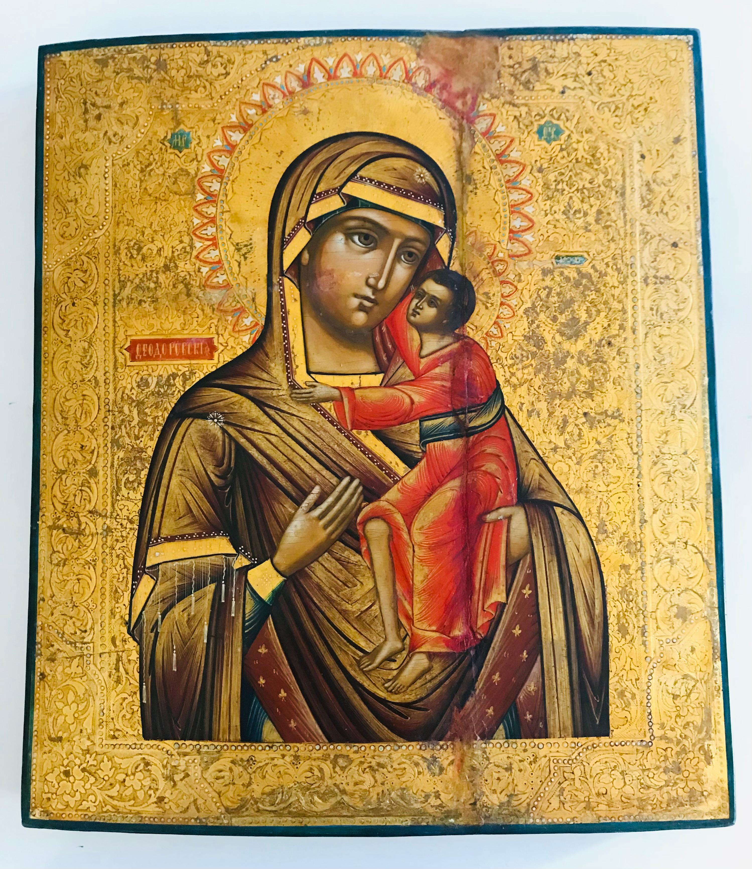 Icono ortodoxo antiguo del siglo XIX: María con el Niño Jesús. Témpera sobre madera sobre fondo ornamentado de pan de oro. Tablas de madera rajadas por el paso del tiempo. restauradas.