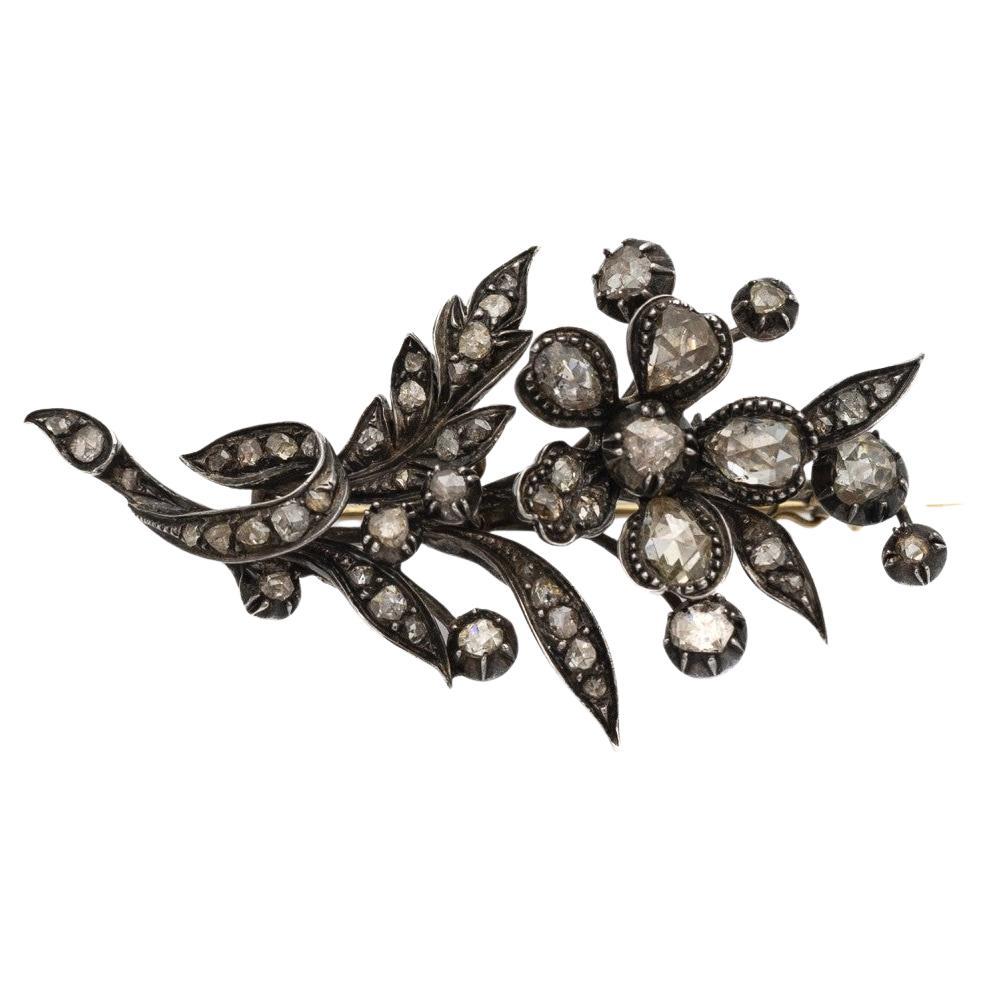 Broche ancienne avec 54 diamants en anciennes coupes hollandaises en rosette (ronde, en goutte d'eau, irrégulière) encadrés dans une construction en or-argent sous la forme d'une brindille feuillue avec une fleur. La forme unique et le travail