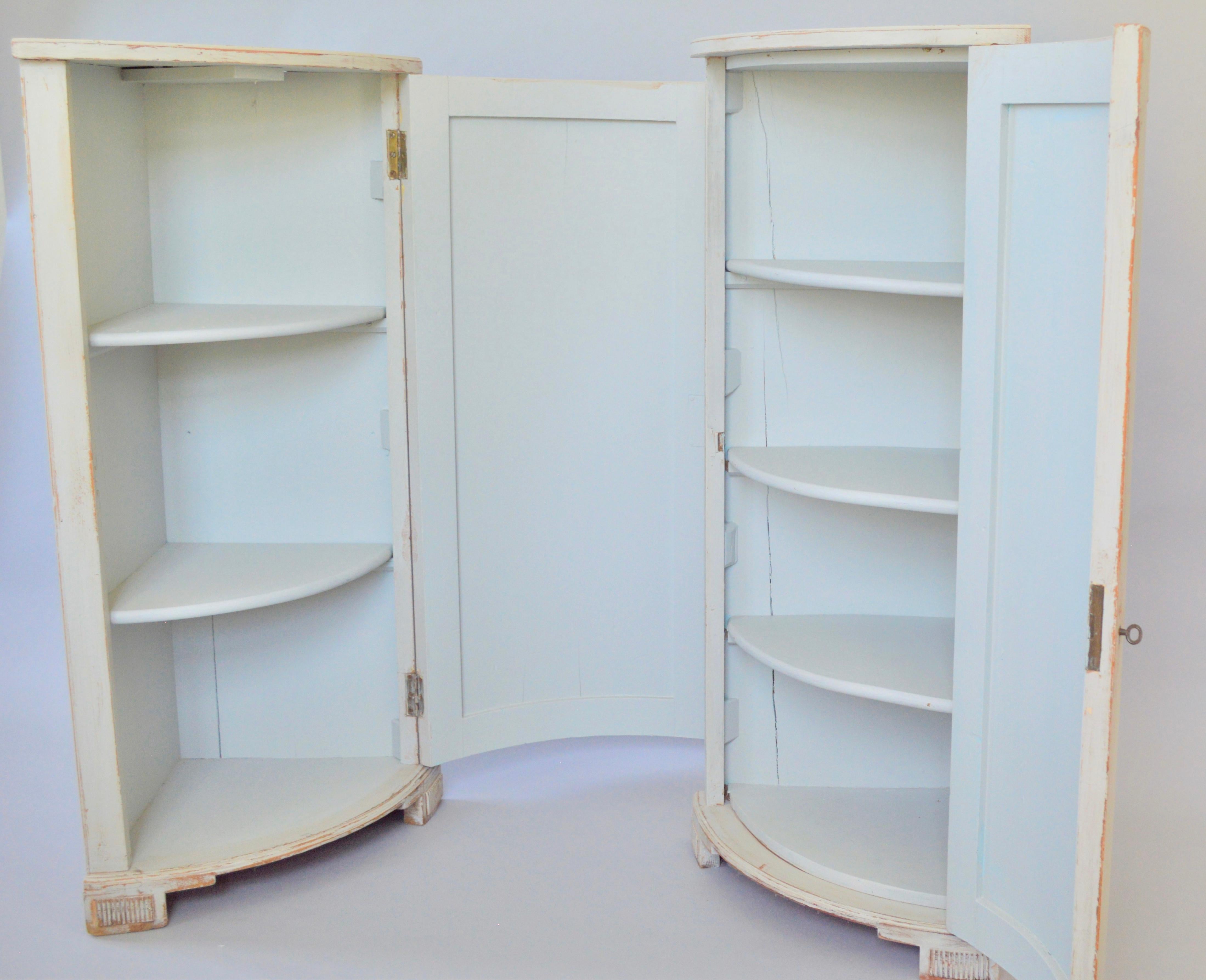 A pair of identical corner cabinets, grisaille grey-blue painted. Richly decorated with hand painted flower urns or vases on the front.
Very high quality painting.
The one has 3 shelves the other one has 4.