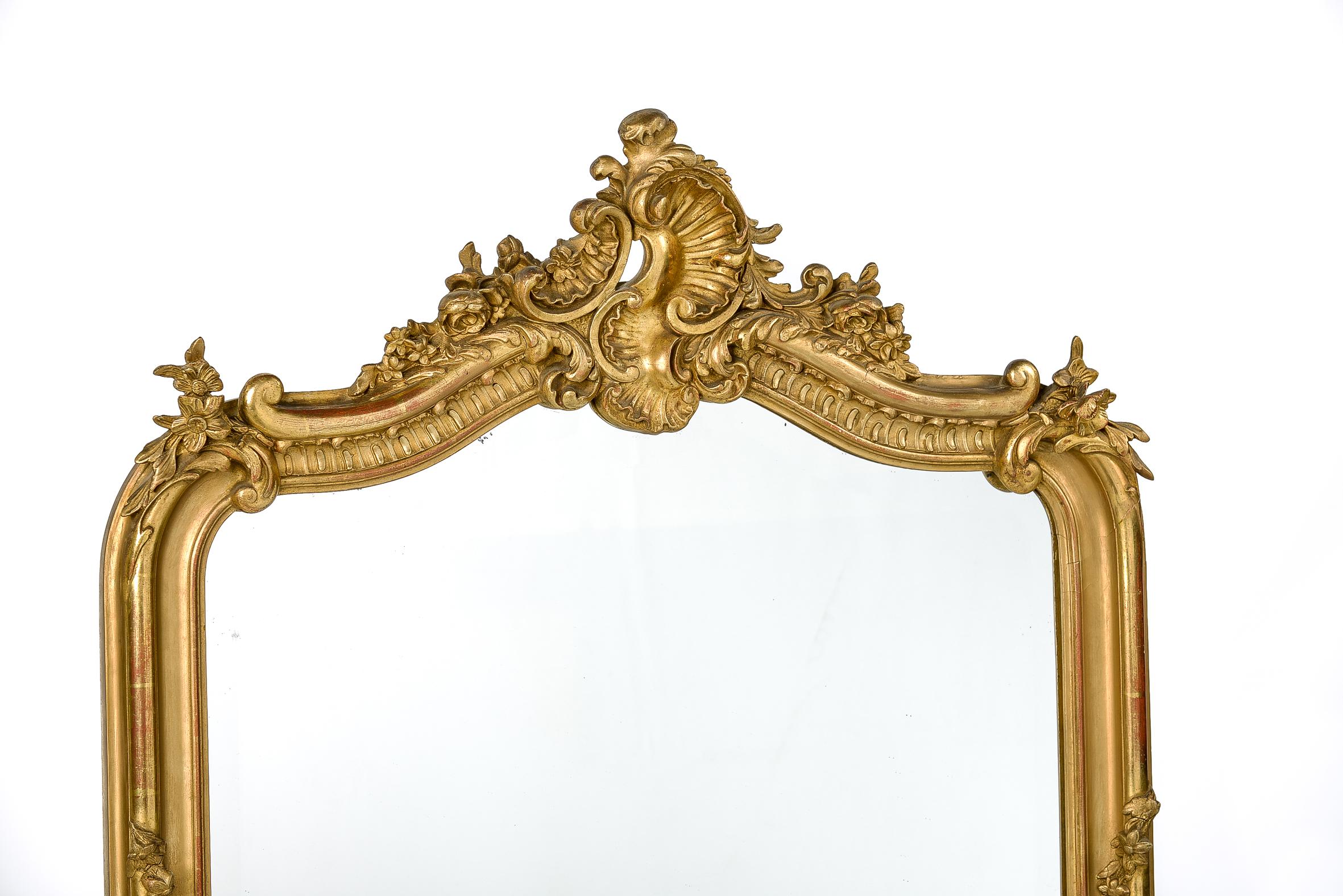 This beautiful antique French gold gilt mirror is a typical Louis Quinze or rococo mirror. It has the typical asymmetrical ornamentation and facetted mirror glass. The mirror is partially gold leaf gilt and partially gold painted. The gold leaf