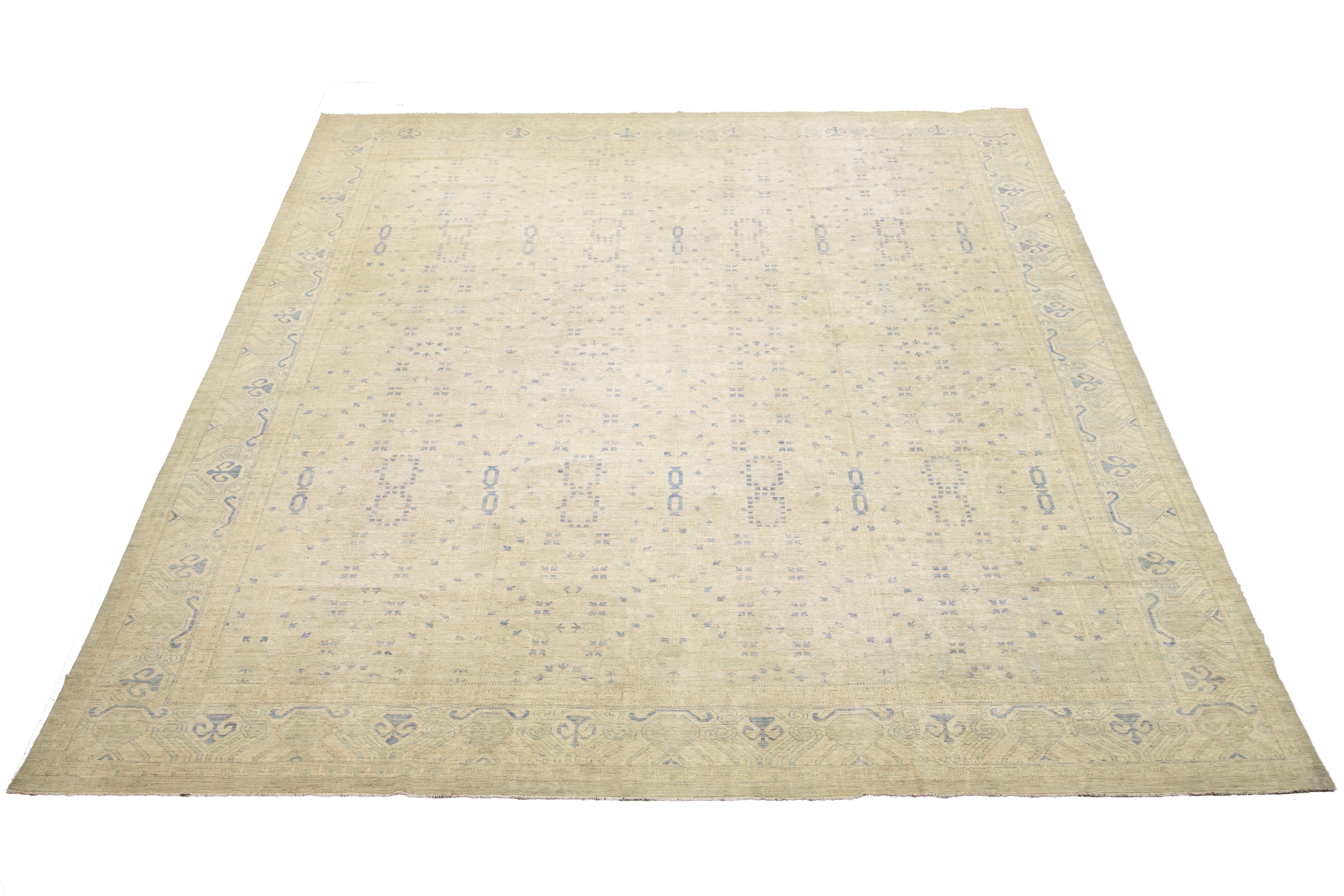 This exceptional oversized modern Khotan-style hand-knotted wool rug features a beige field. The artwork is elegantly framed and presents a sophisticated all-over pattern in blue, showcasing its exquisite design.
This rug measures 19'2