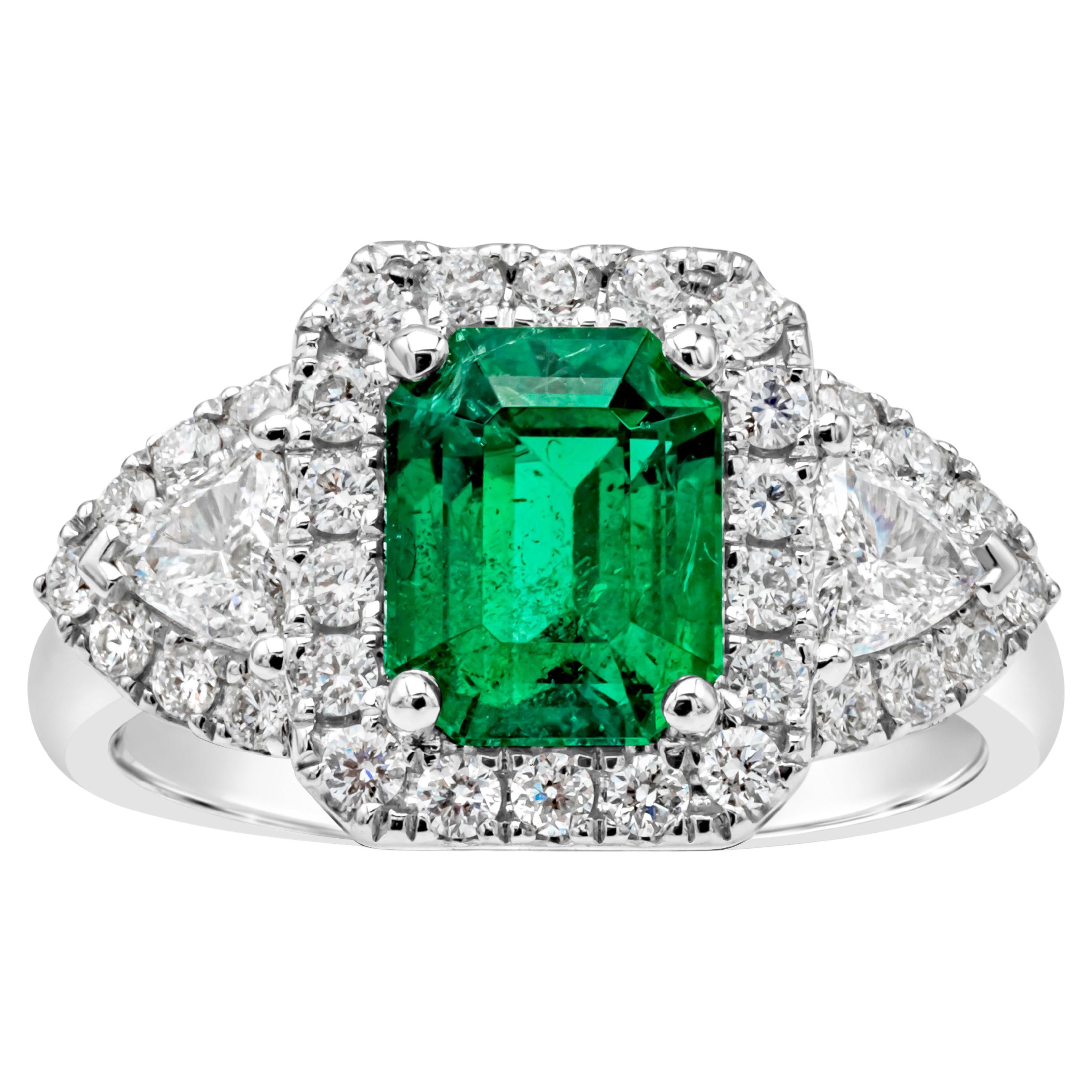 This stunning and beautiful three stone halo engagement ring features a GRS certified 1.90 carats emerald cut green emerald, set in a classic four prong setting. Flanked on each side are brilliant trillion cut diamonds weighing 0.29 carats total, F