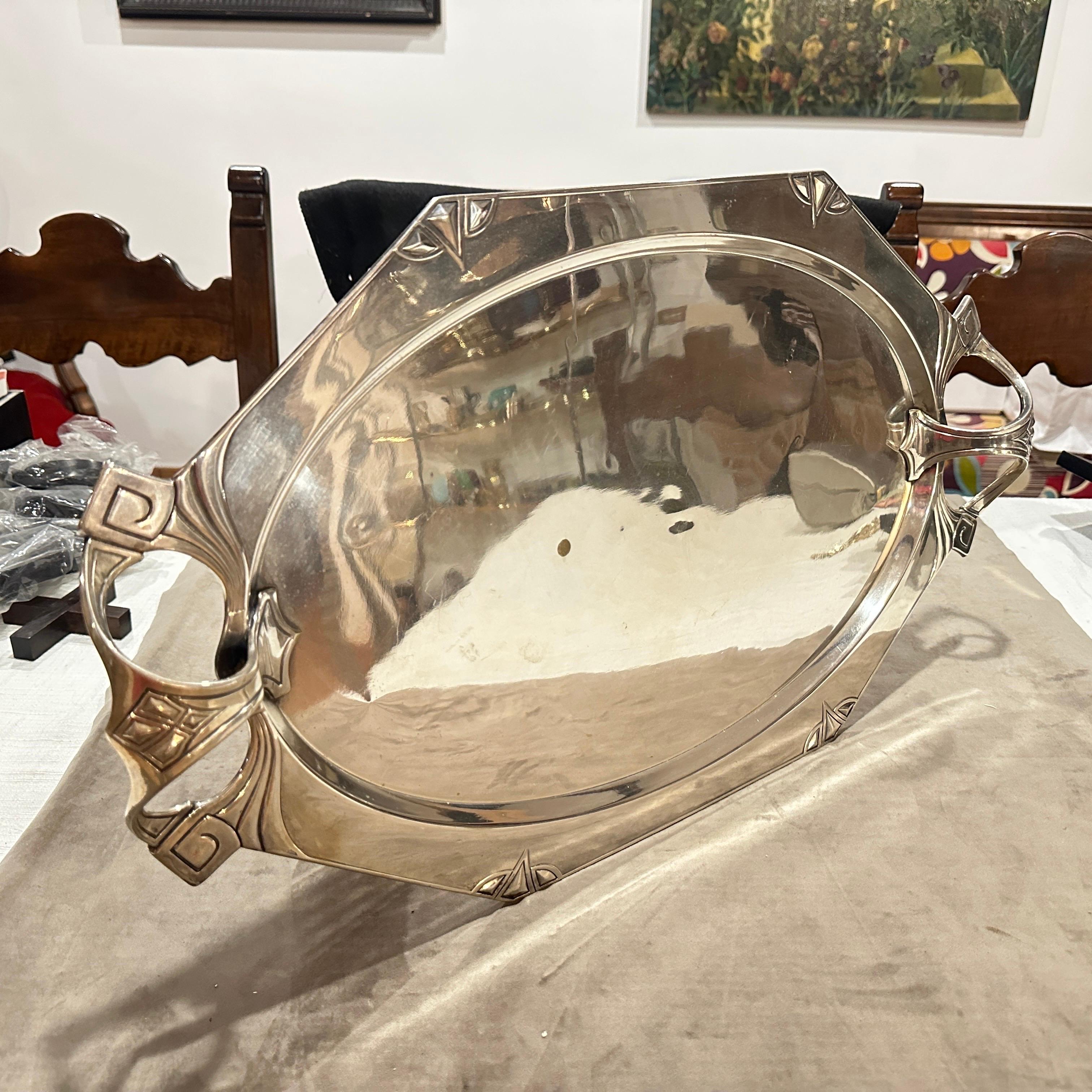 A 1900 silver plated oval tray designed by Albert Kohler and Cie for WMF, twin handled, octagonal oval form embossed with geometric diamond corners and whiplash handles. Richly decorated with embossed patterns that combine the lyrical curves of Art