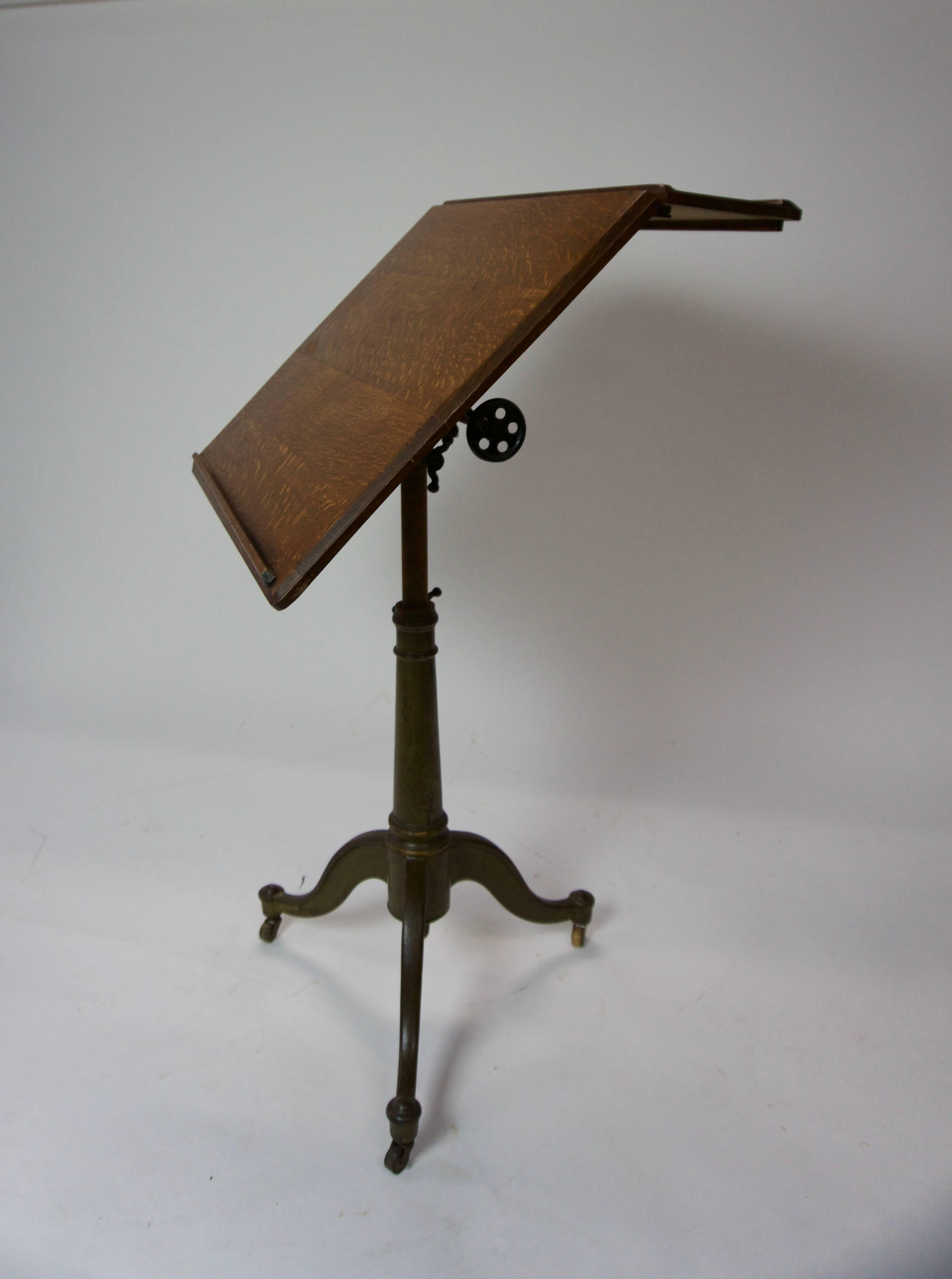 Cast iron base stand with a tan/brown paint color. Typical wear on the paint. Solid oak top will fold to almost flat. Has a few scuffs and minor scratches. One wheel adjustment. Wheels roll nicely, but are not permanently welded in. Height is