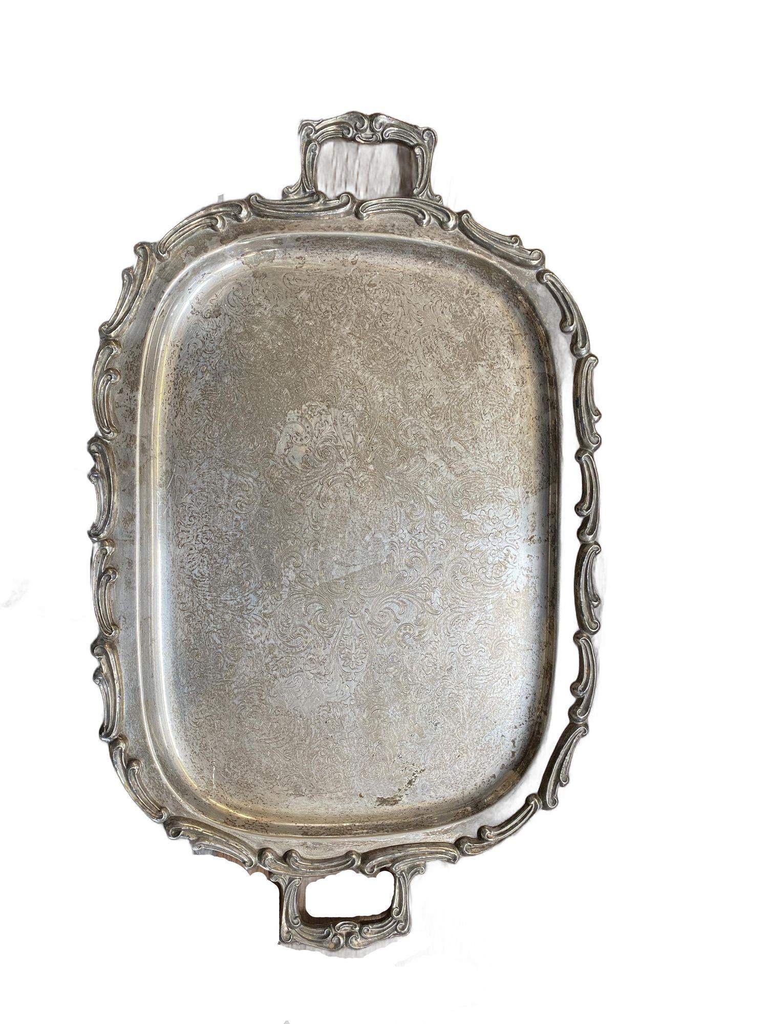 This exquisite silverplate serving tray dates back to 1900, boasting a stunning scrollwork design adorned with shells. Stamped with the 