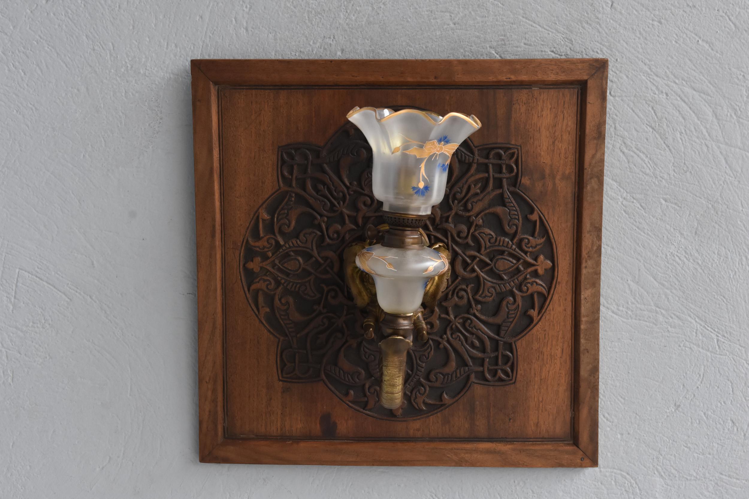 Elephant wall lamp from 1900 in bronze mounted on a carved wooden mandala. Glass tulip painted in gold.