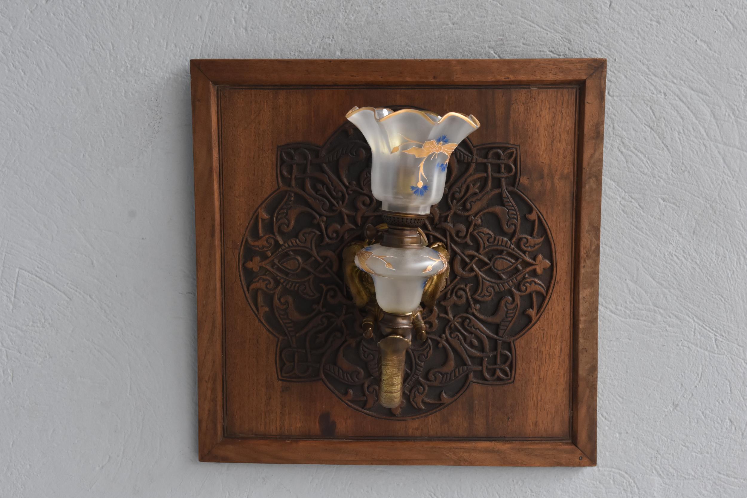 Lampada da parete a forma di elefante del 1900 in bronzo montato su un mandala di legno intagliato. Tulipano di vetro dipinto in oro.