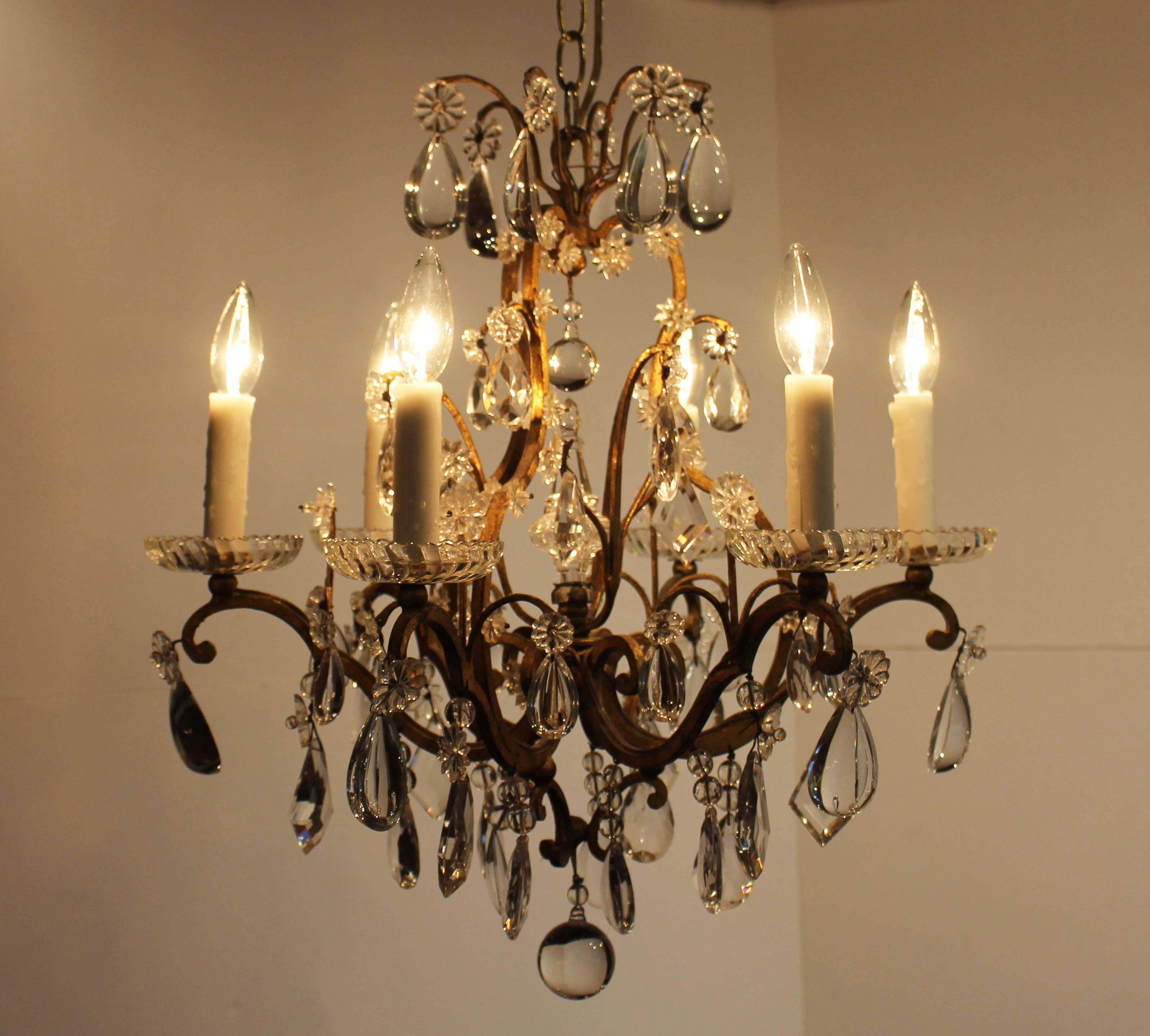 Circa 1900, Louis XV style, 6-light gilt iron & crystal chandelier, French. Very good quality, S & C scrolled iron work with abundant tear-drop, faceted diamond, and ball drops accented with rosettes & beads. Panel swirled bobeches. 

Founded by