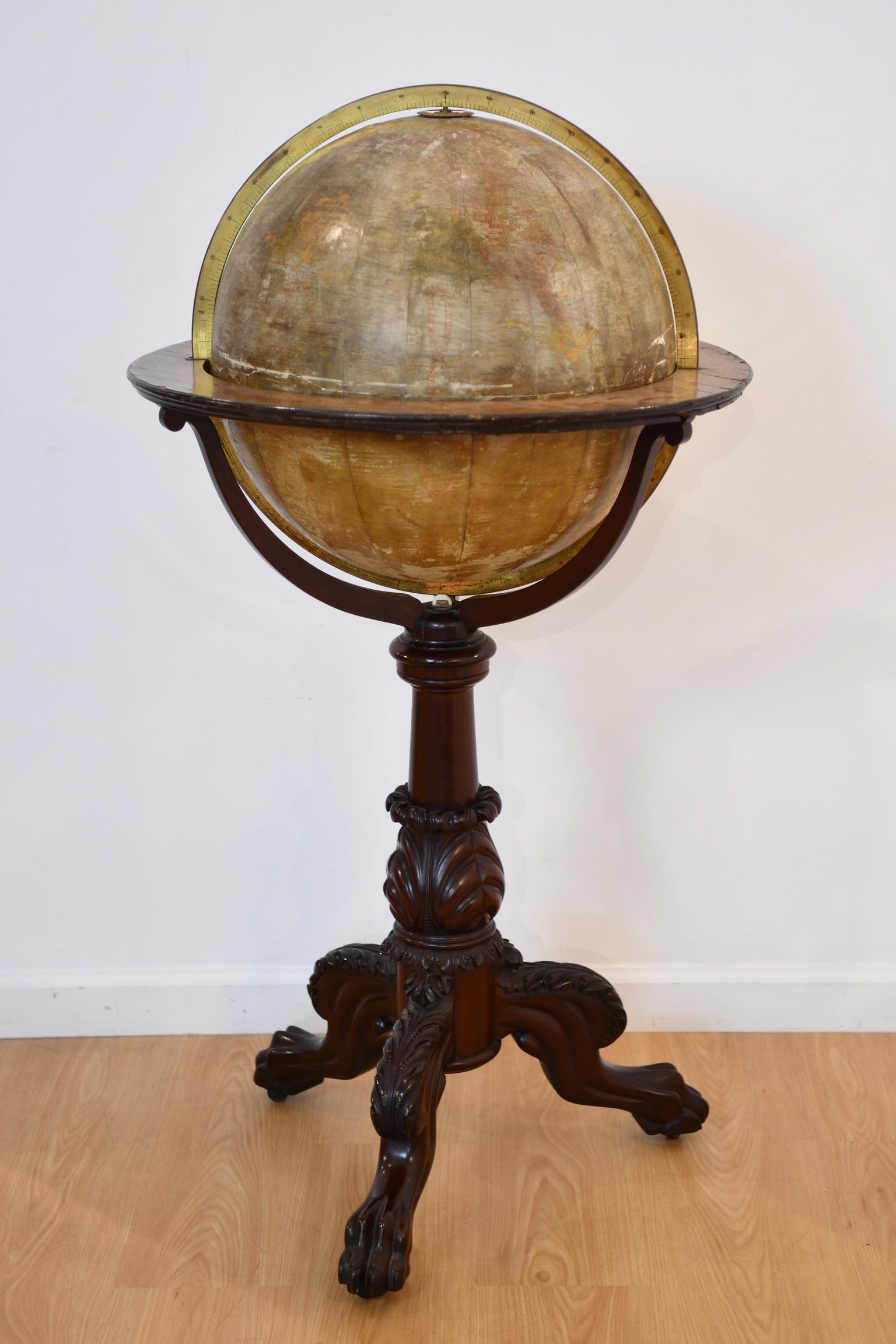 Terrestrial floor globe with a large cartouche to the Pacific Ocean, supported in a graduated brass meridian with a mahogany horizon band with paper zodiac and calendar. Globe raised on a carved classical revival mahogany tripod stand with acanthus