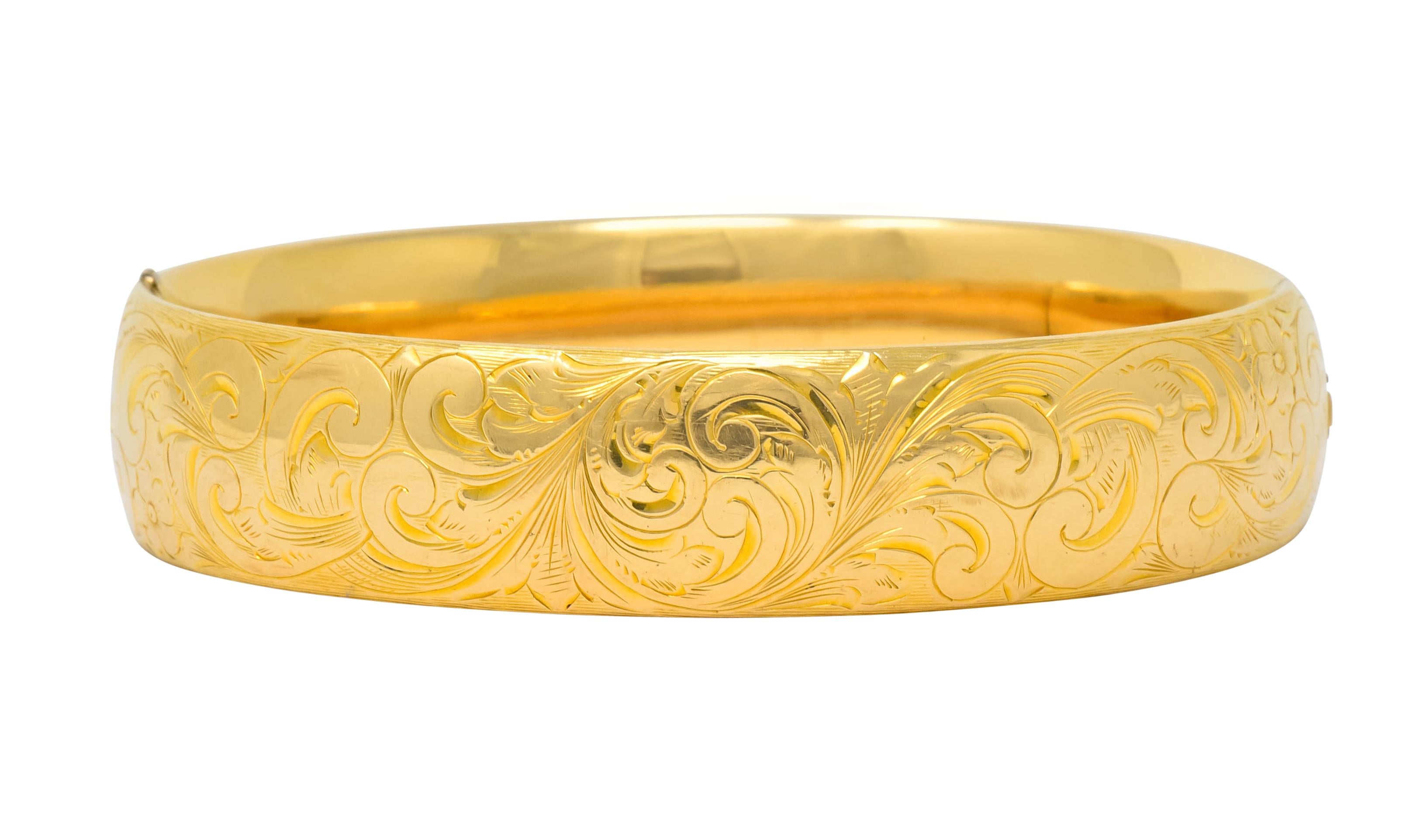 Bangle style bracelet deeply engraved throughout with scrolling foliate whiplash accented by floral motifs

Concealed clasp that opens on a hinge

With maker's mark and stamped 14k for 14 karat gold

Circa 1900

Inner circumference: 6 3/4