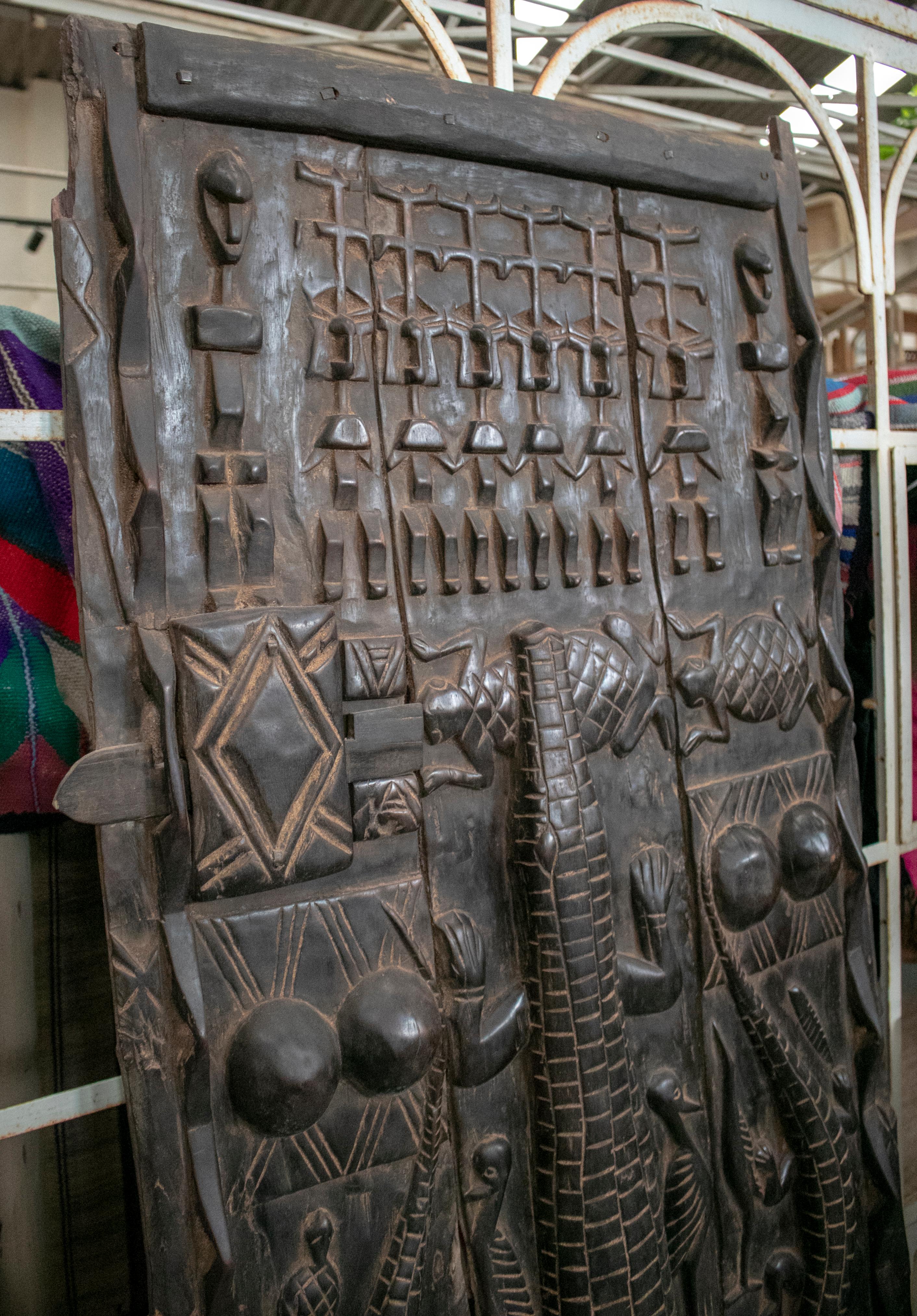 1900s African wooden door with hand carved ethnic human and animal relief.