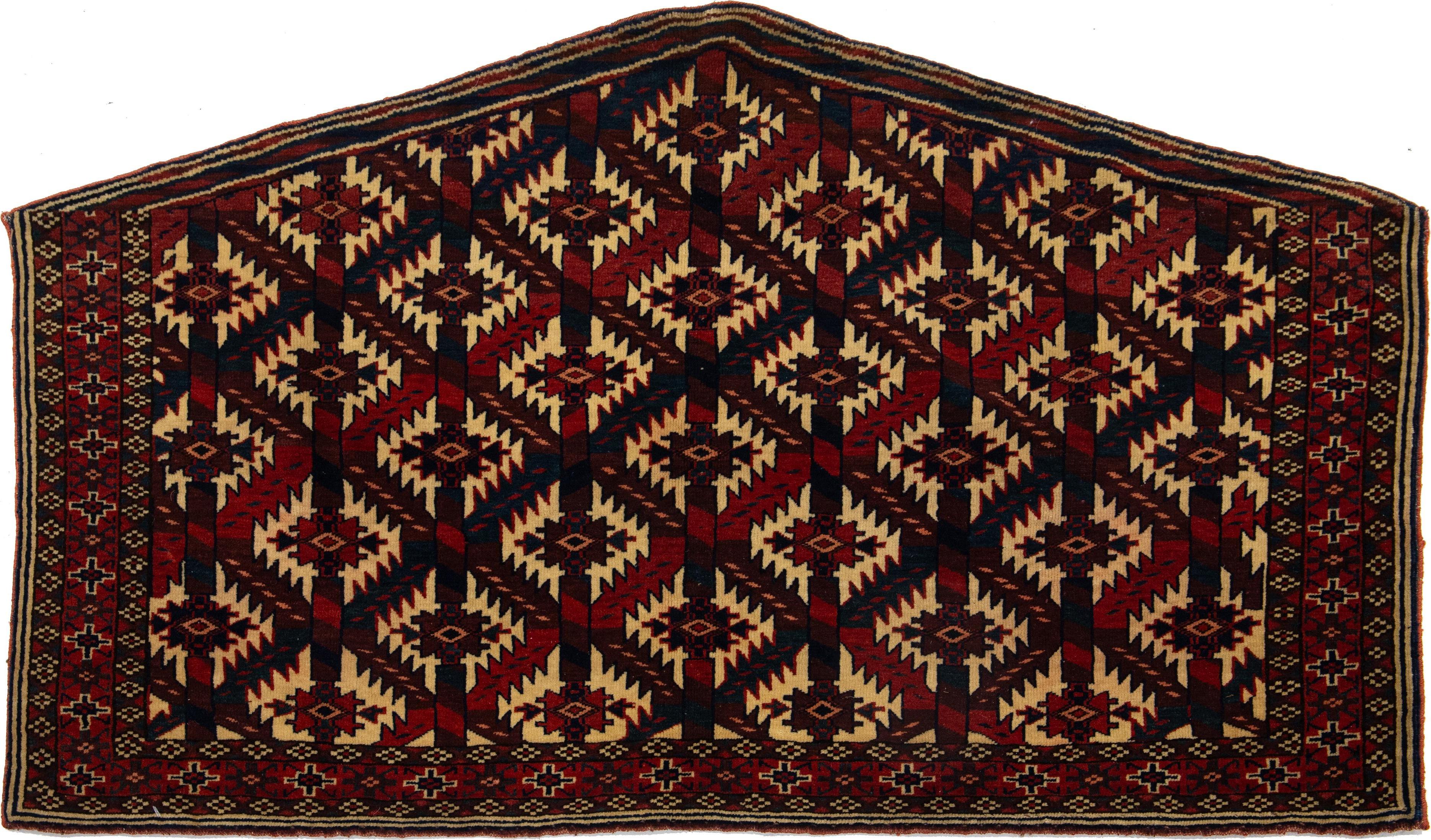 Ce tapis antique en laine Yamoud se distingue par sa couleur bordeaux et son impressionnant motif géométrique dans les tons bleu marine, rouge et beige.

Ce tapis mesure 2'4