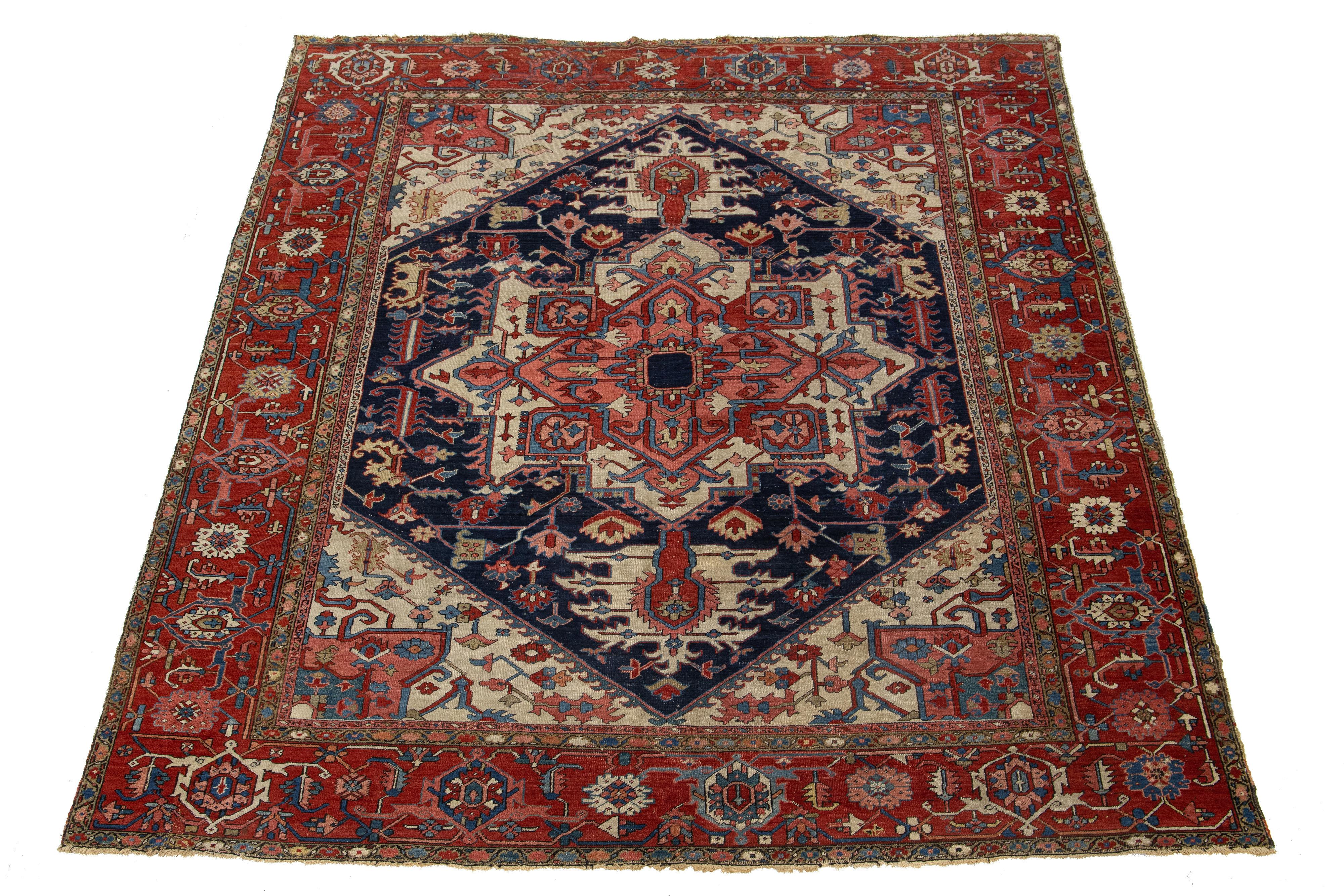 Un ancien tapis persan en laine Heriz présentant un motif allover rose, rouge et beige vibrant sur un fond bleu marine profond.

Ce tapis mesure 9'4'' x 11'5''.

