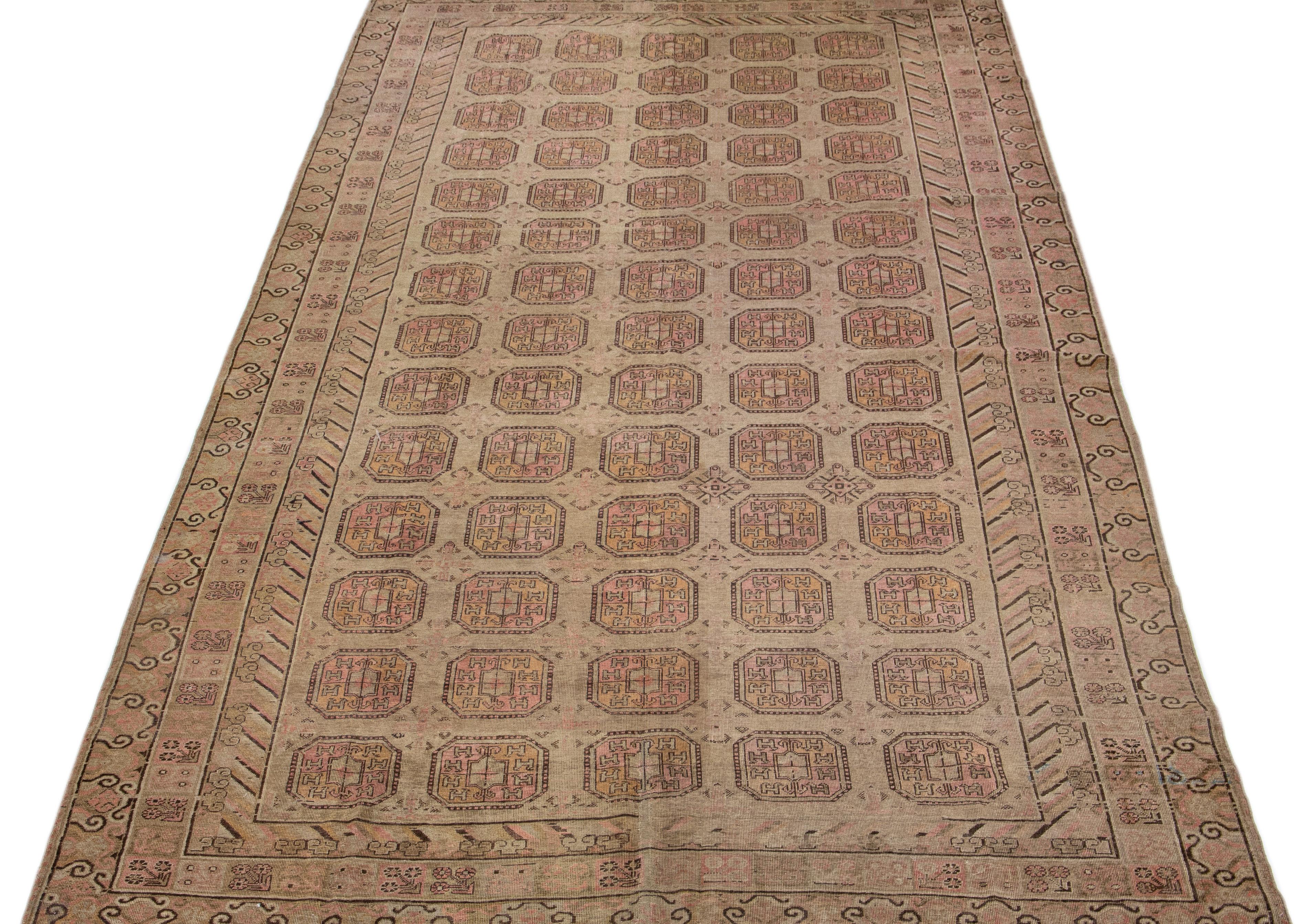 Beautiful antique Khotan hand-knotted wool rug with a brown color field. This Khotan rug has pink, orange, and dark brown accents in a gorgeous geometric multi-medallion pattern. 

This rug measures 8'9