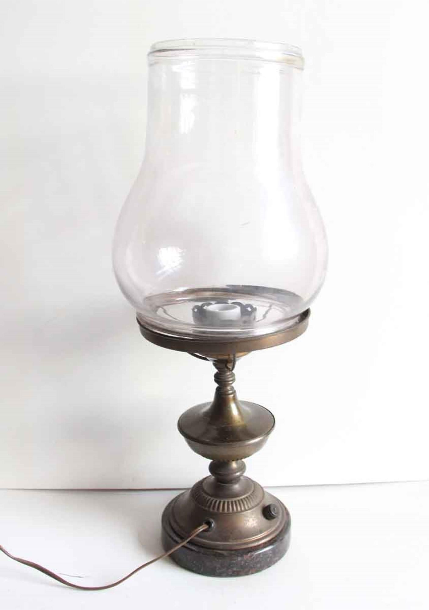 1900s industrial brass desk lamp with a large clear glass shade, dark patina and black marble base. The glass is stamped Dietz Pioneer. This was originally an oil lamp and was converted to electricity. This can be seen at our 400 Gilligan St