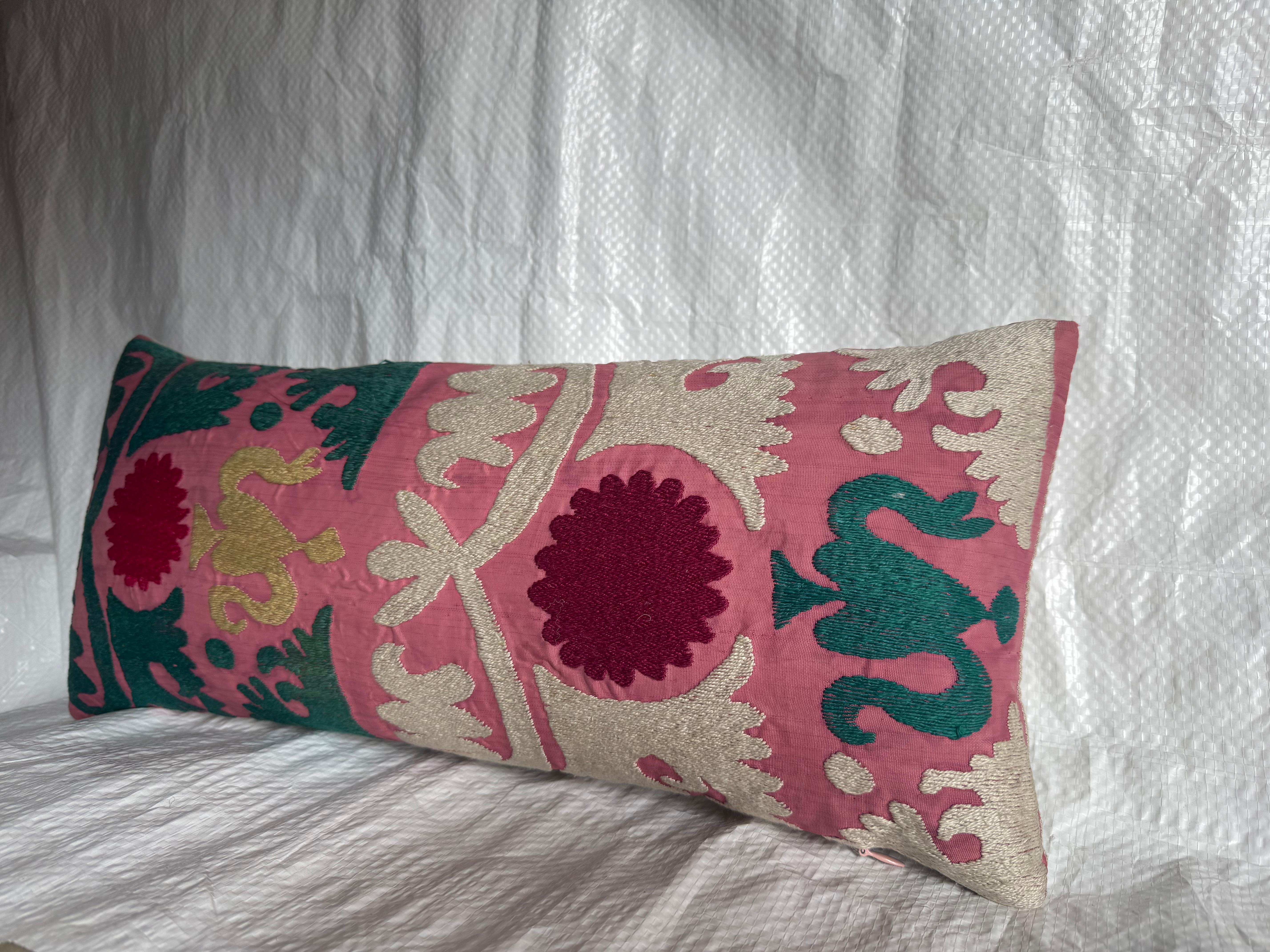 Exceptionnel coussin lombaire Suzani d'Asie centrale, datant du début des années 1900. Ce textile brodé à la main présente des médaillons floraux audacieux et des volutes de vigne stylisées, exécutés dans des tons vifs de rouge, de vert, d'ivoire et