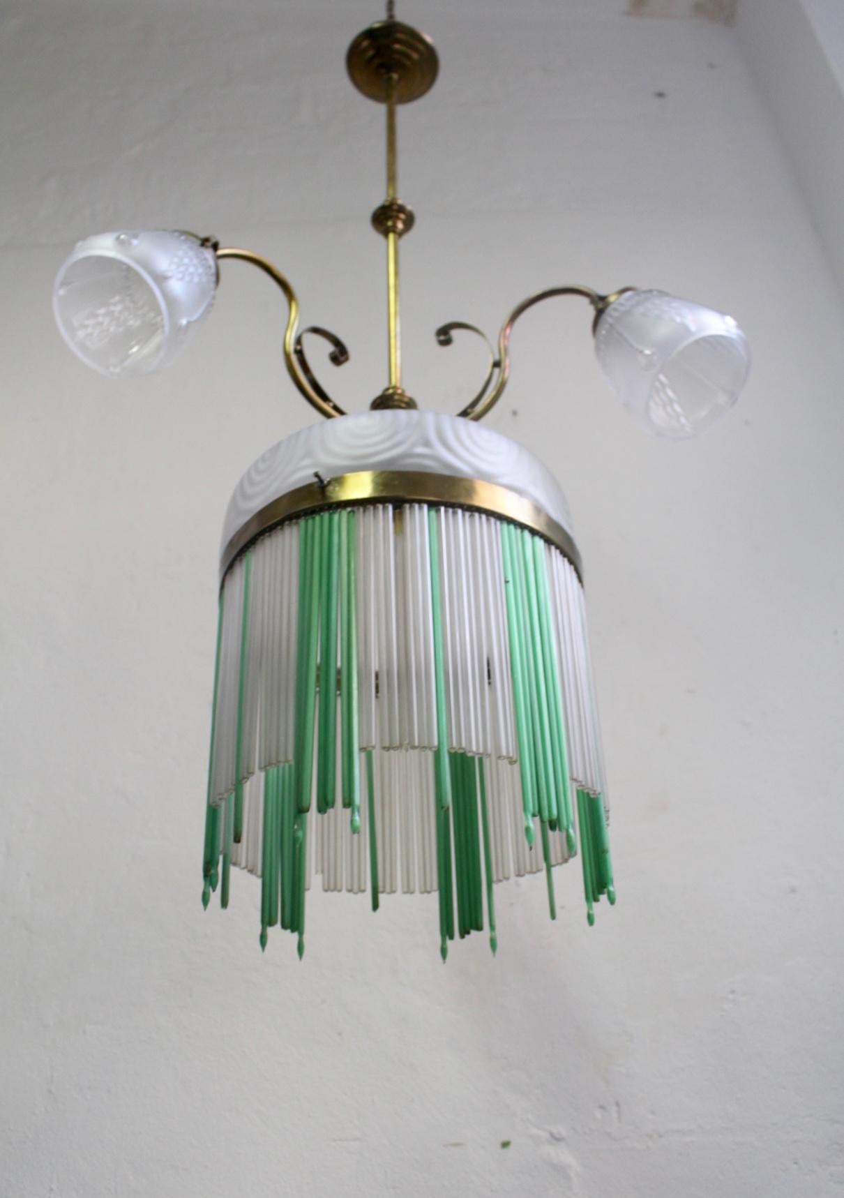 Art Nouveau 4-lights chandelier with brass structure, frosted carved glass and glass pendant sticks hanging from the center brass ring.
Good Vintage Condition. Some Pendant sticks featuring some minor wear.