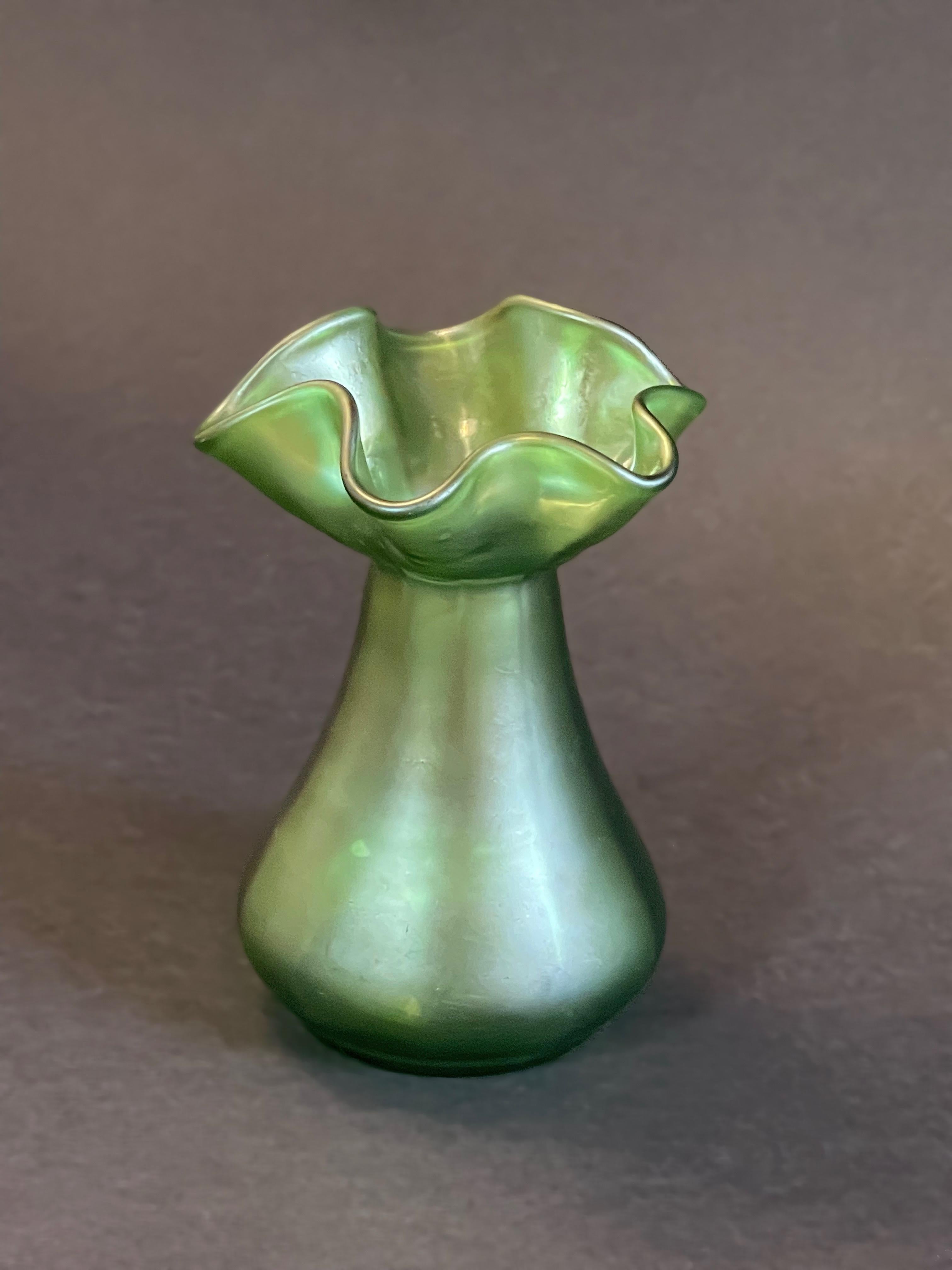 Absolutely marvellous antique vase in a very mildly iridescent green, attributed to Loetz Witwe.
Bohemia around 1900.
This small sea urchin and equally floral shaped vase is somewhat impressive.
The finish seems to be velvety matte, yet in a certain
