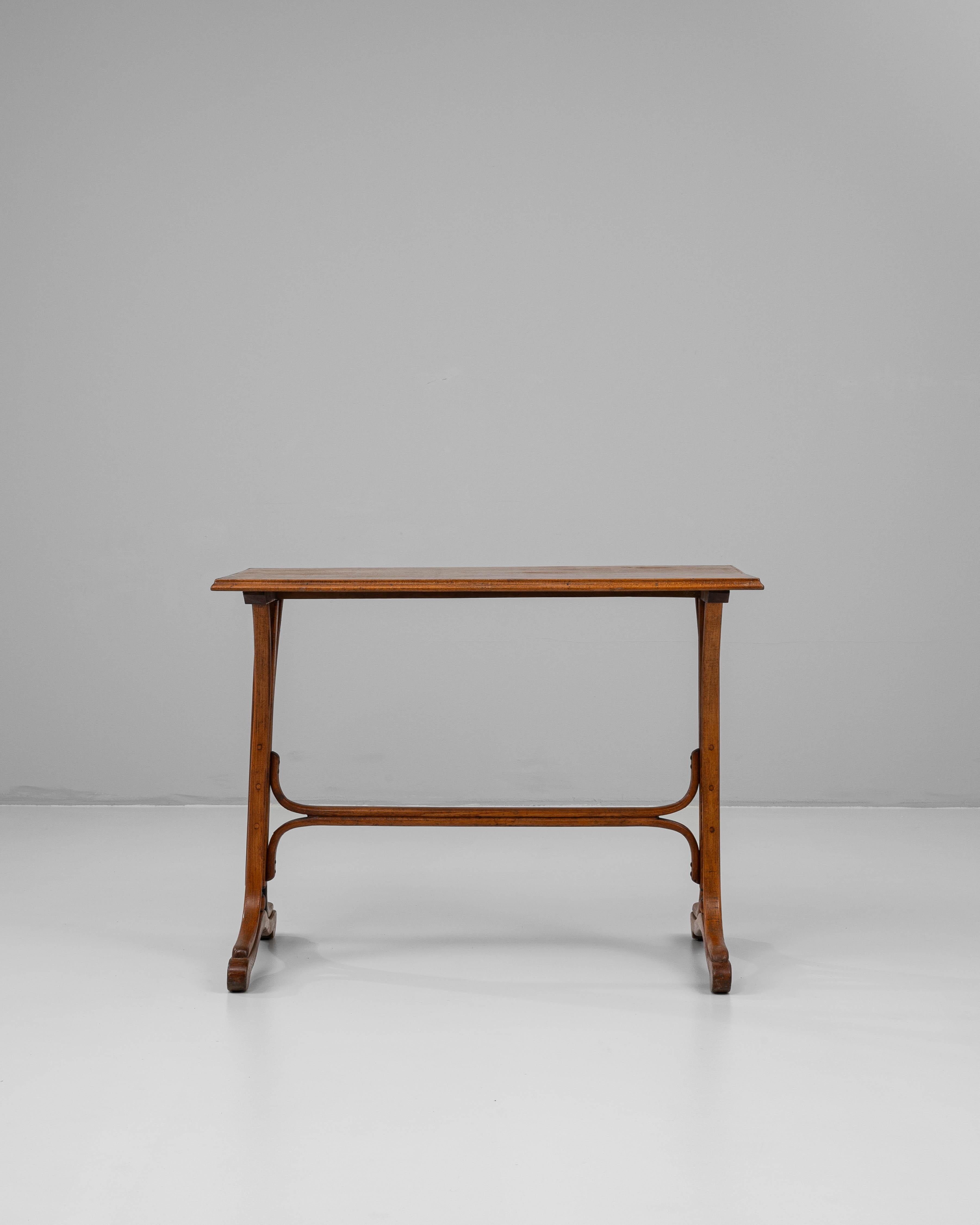 This 1900s Austrian wooden side table showcases the refined craftsmanship and elegant design characteristic of early 20th-century Viennese furniture. Crafted in richly patinated wood, the table features a sculptural base with gently curved supports
