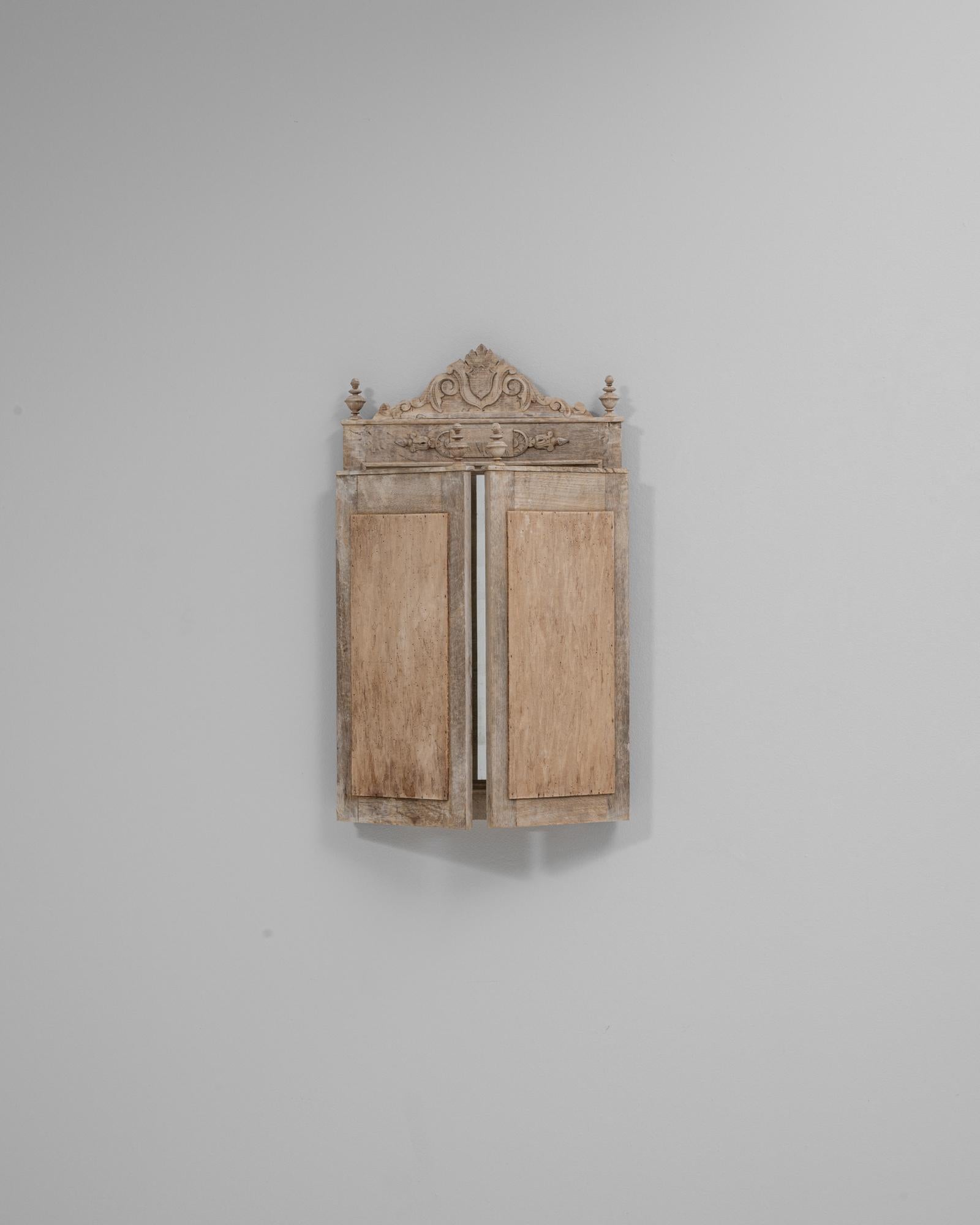 This 1900s Belgian carved oak folding wall mirror presents a beautifully aged patina and refined architectural presence, highlighted by its tri-panel design and ornate crest. The central mirror is framed by two hinged side panels that fold inward,