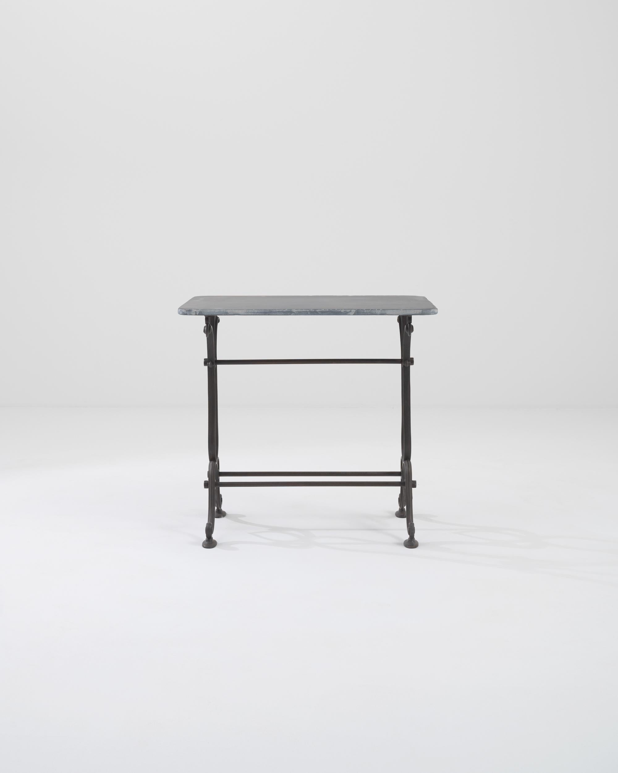 A metal bistro table with a marble top made in 1900s, France. Cast foliate motifs cap the ends of either side of this marvelous table, accentuating the dignity and confidence it embodies. The stark contrast of light marble and dark wrought iron