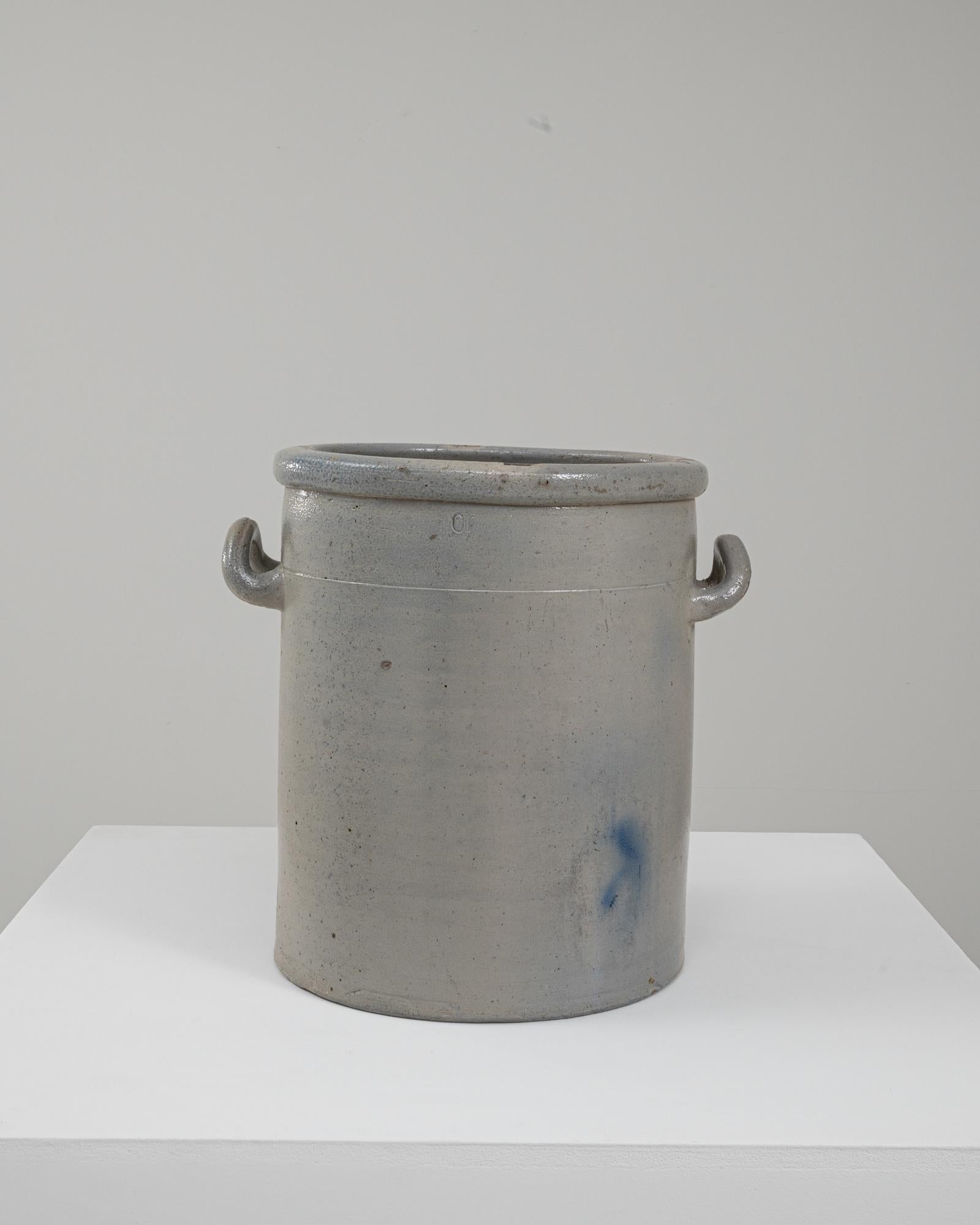 Vaso in ceramica belga del 1900. Questo robusto e utilitario vaso in ceramica riflette la pratica abilità artigianale caratteristica del gres belga dei primi del Novecento. La sua forma alta e cilindrica è rifinita con un morbido smalto grigio con