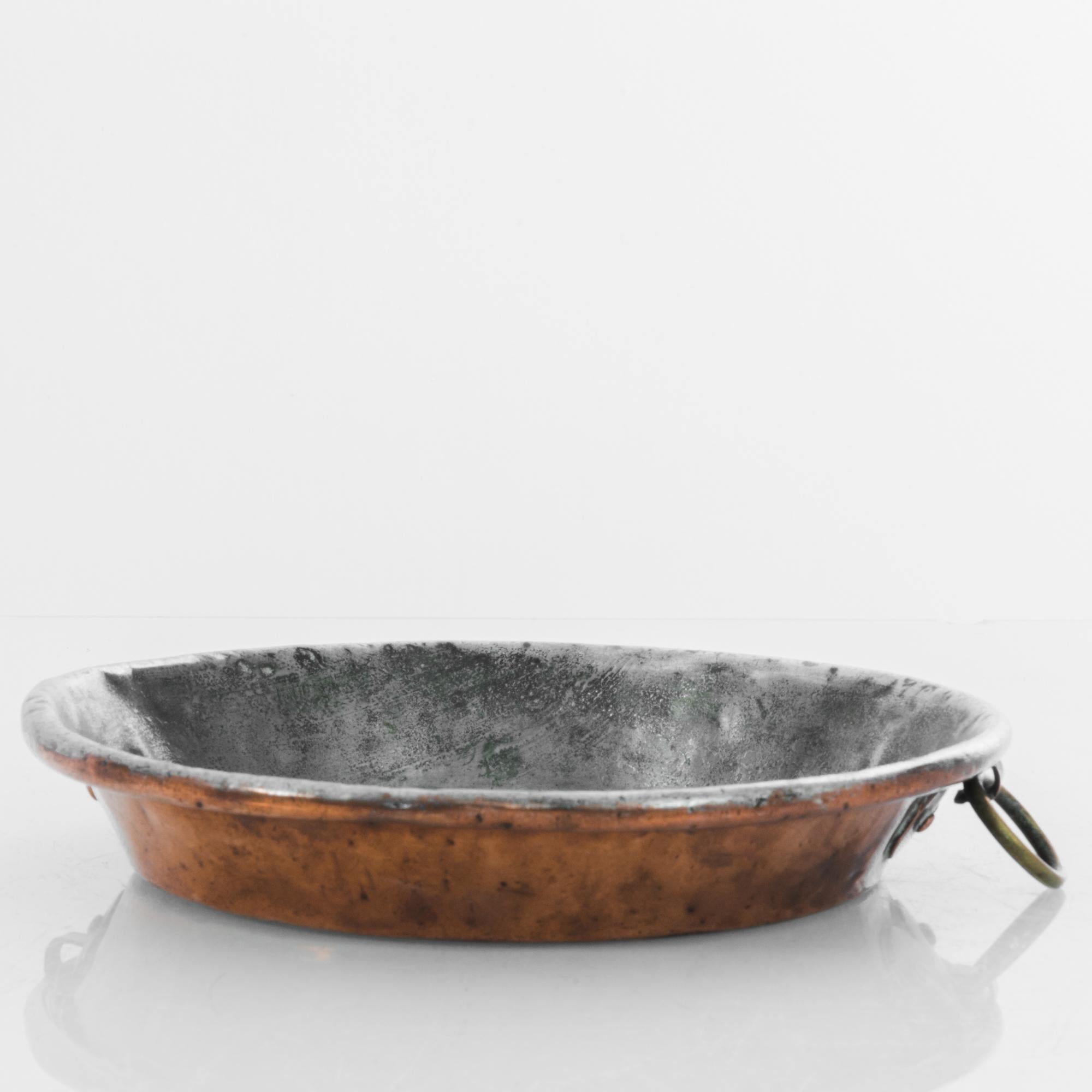 A copper pan from turn of the century Belgium. One of the best metals for conducting heat evenly, copper has been used for sauces, jams and marmalade making for centuries. A low round shape, with upraised handles; the rich, rosy tone of the metal