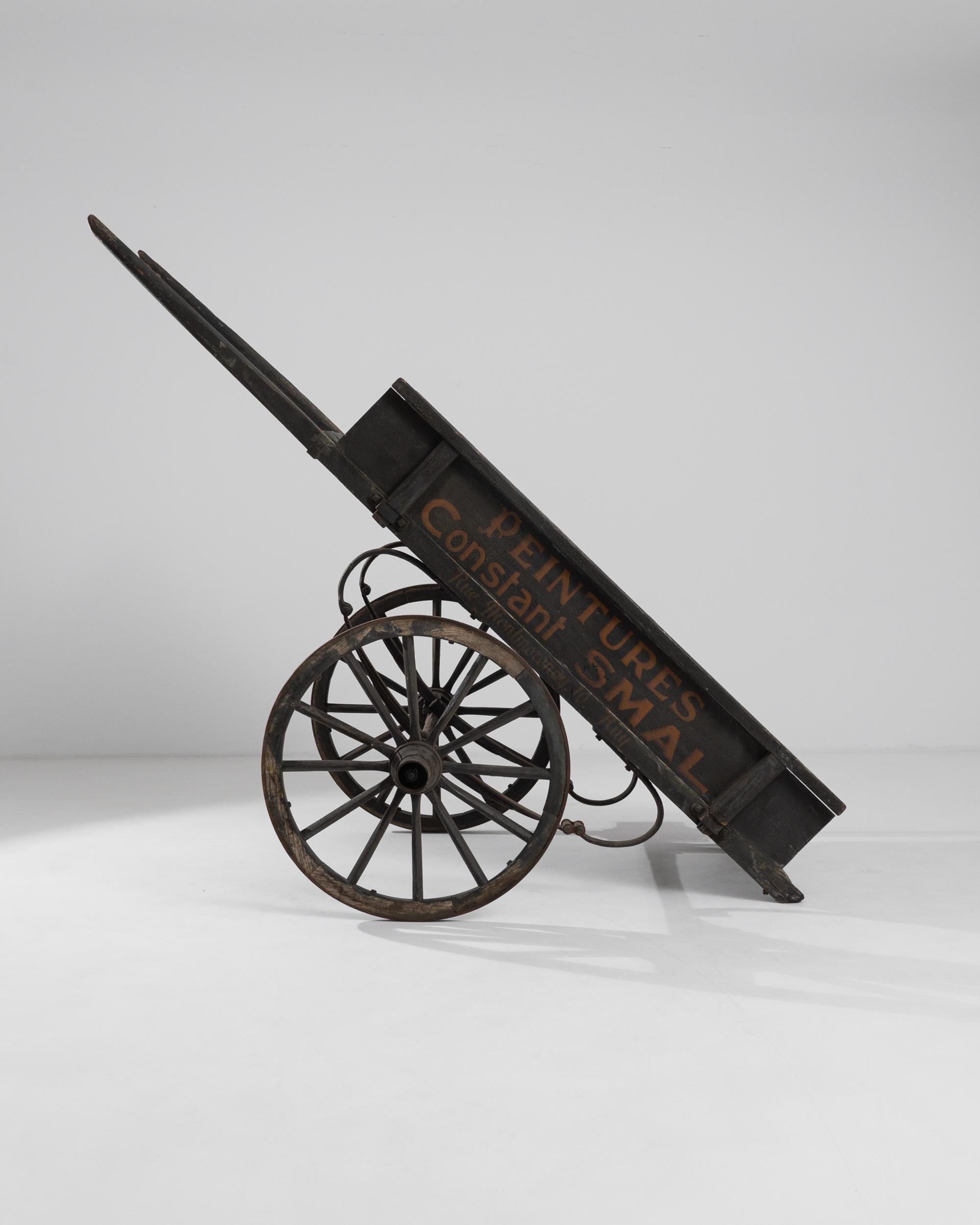 This antique wooden carriage was produced in 1900 in Belgium. A large carriage painted in black, displaying the inscription “Peintures Constant Smal” in dark red lettering. Standing firm on sturdy wheels, the wooden cart conjures the daily routine