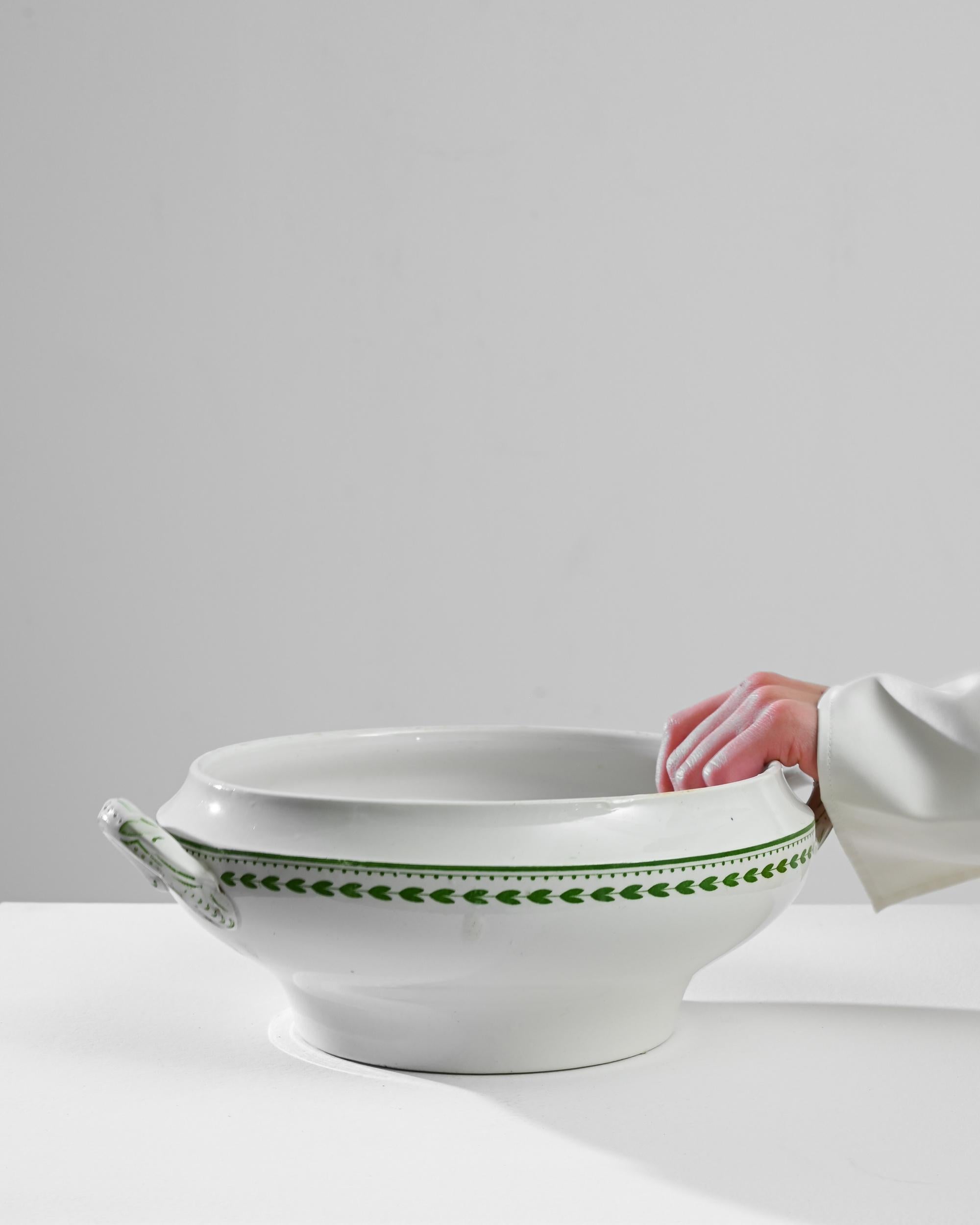 This 1900s Belgian Porcelain Tureen from Boch Frères La Louvière is a delightful blend of simplicity and elegance. Crafted during a time when attention to detail was paramount, this piece features delicate green leaf motifs that encircle the bowl,