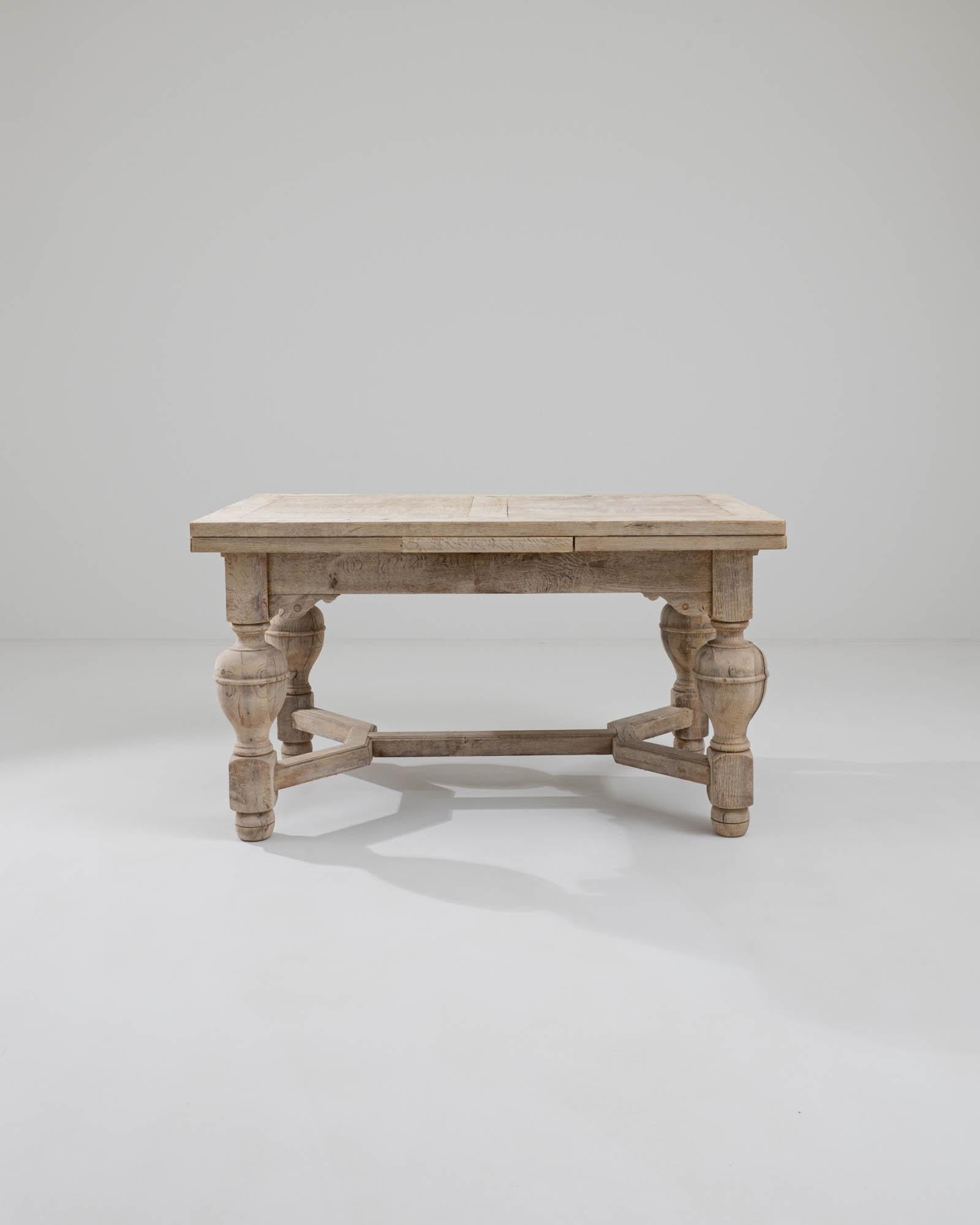 A wooden dining table made in Belgium circa 1900. Four strong and sturdy legs, lathed into sumptuous curves buttress this bold table with classical good looks. With two extra leaves, expanding the expansive surface area of this regal dining area,