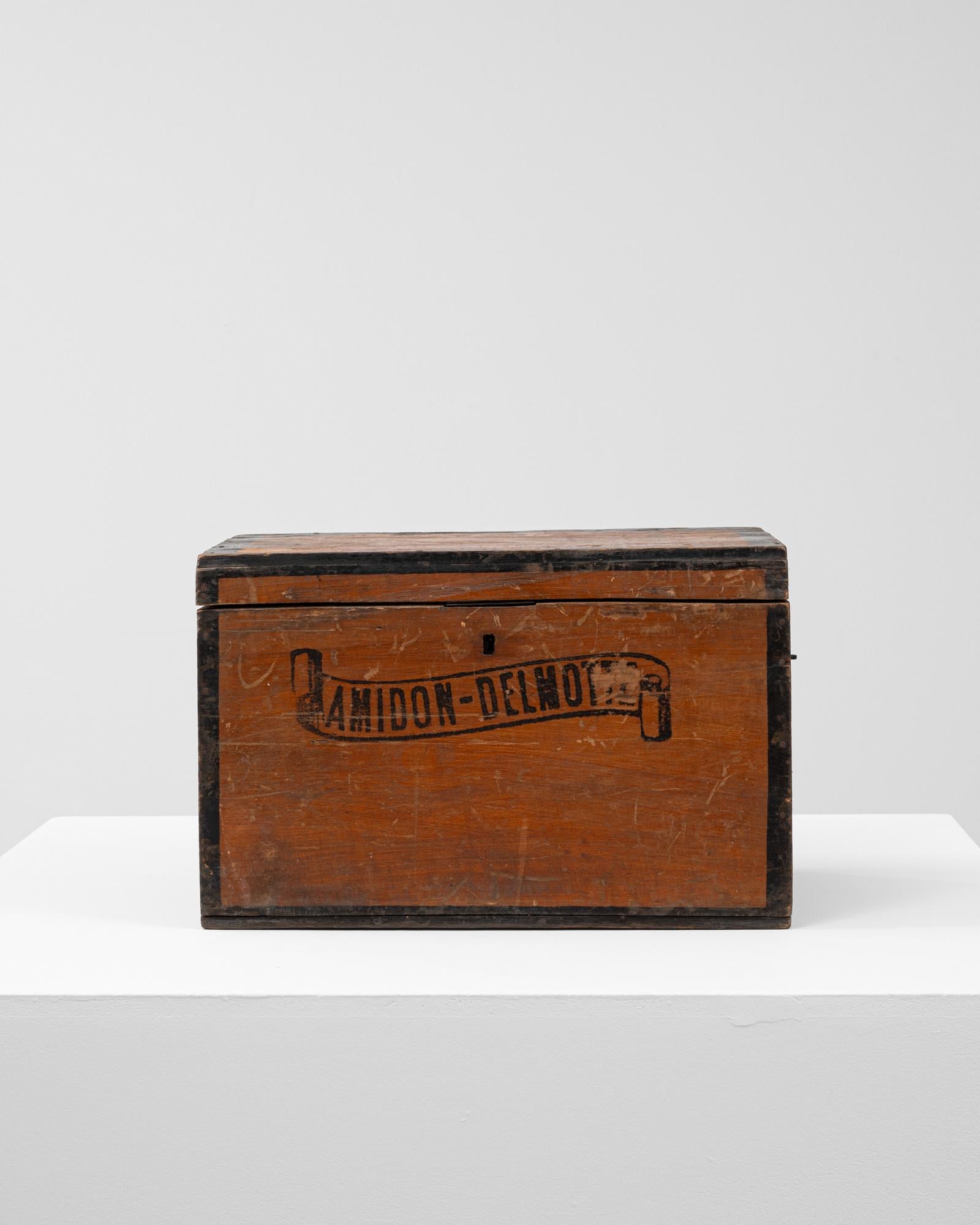 Questa cassapanca belga del 1900 è un affascinante esempio di design utilitaristico dei primi del Novecento, con scritte a stencil che recitano 