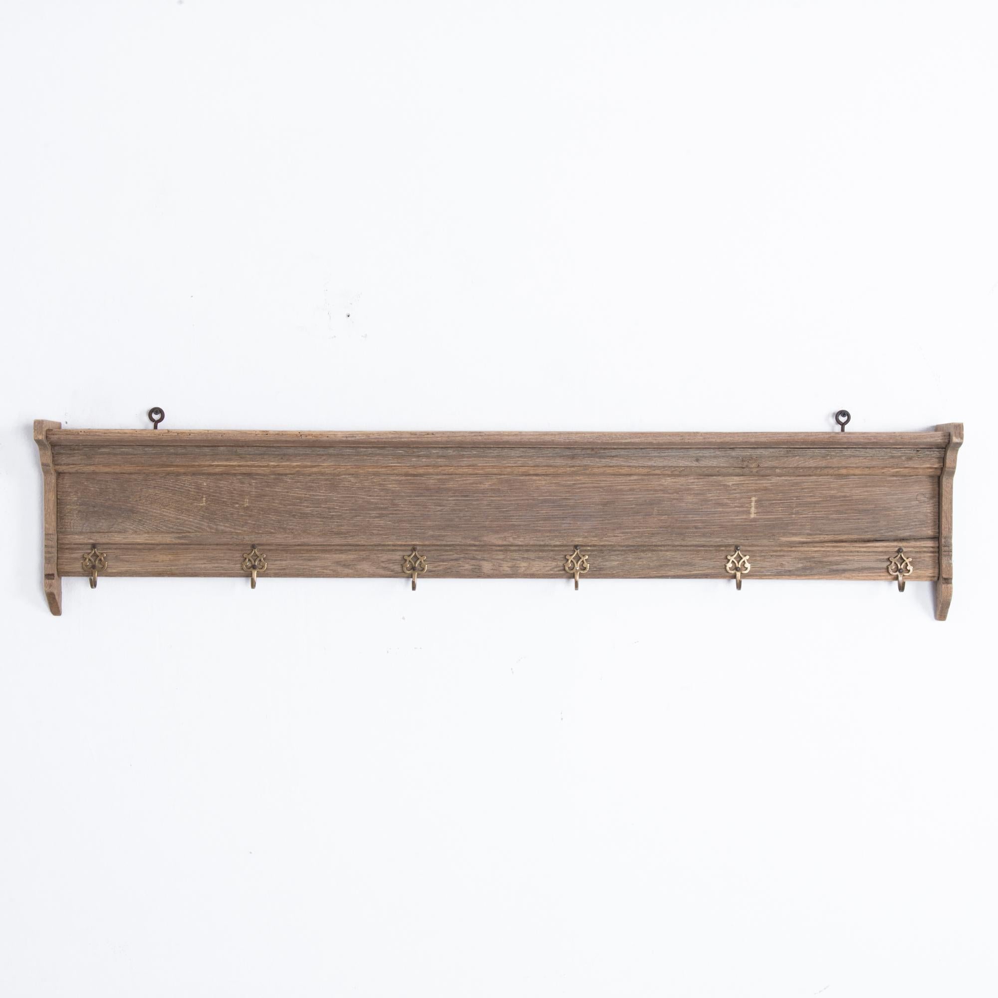 This wooden wall coat rack was made in Belgium, circa 1900 and offers a touch of elegance to your entryway. Mounted on the wall using two screw eyes on top, the rack features crown molding on the upper section, side brackets, and six U-hooks with