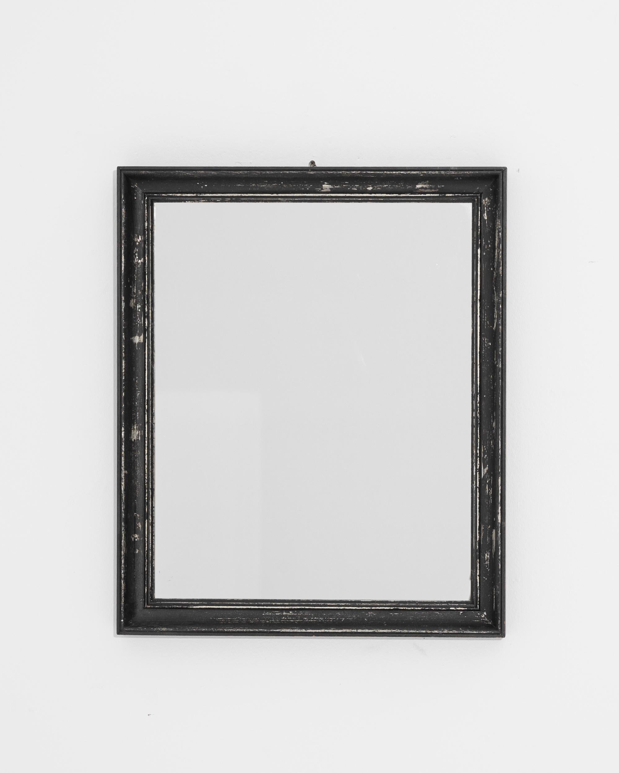 This antique wooden mirror was produced in France, circa 1900. A rectangular wooden frame is carved with a concave profile, a functional statement piece that imparts an elegant simplicity. Slightly patinated, the lustrous black paint reveals white