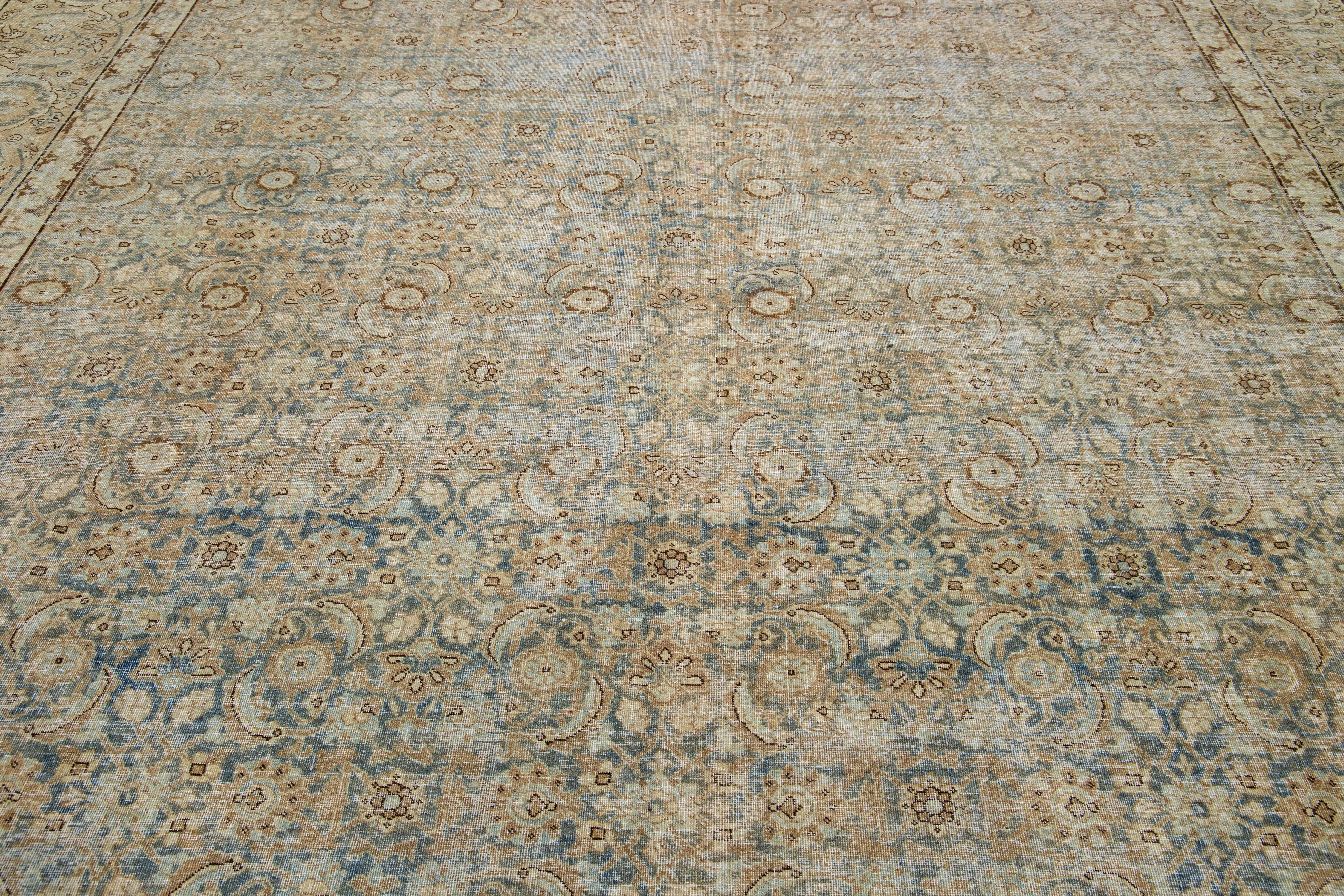Ce tapis persan Tabriz antique des années 1900 présente un champ bleu avec un motif floral captivant accentué par d'élégants détails beiges et bruns.

Ce tapis mesure 11'4