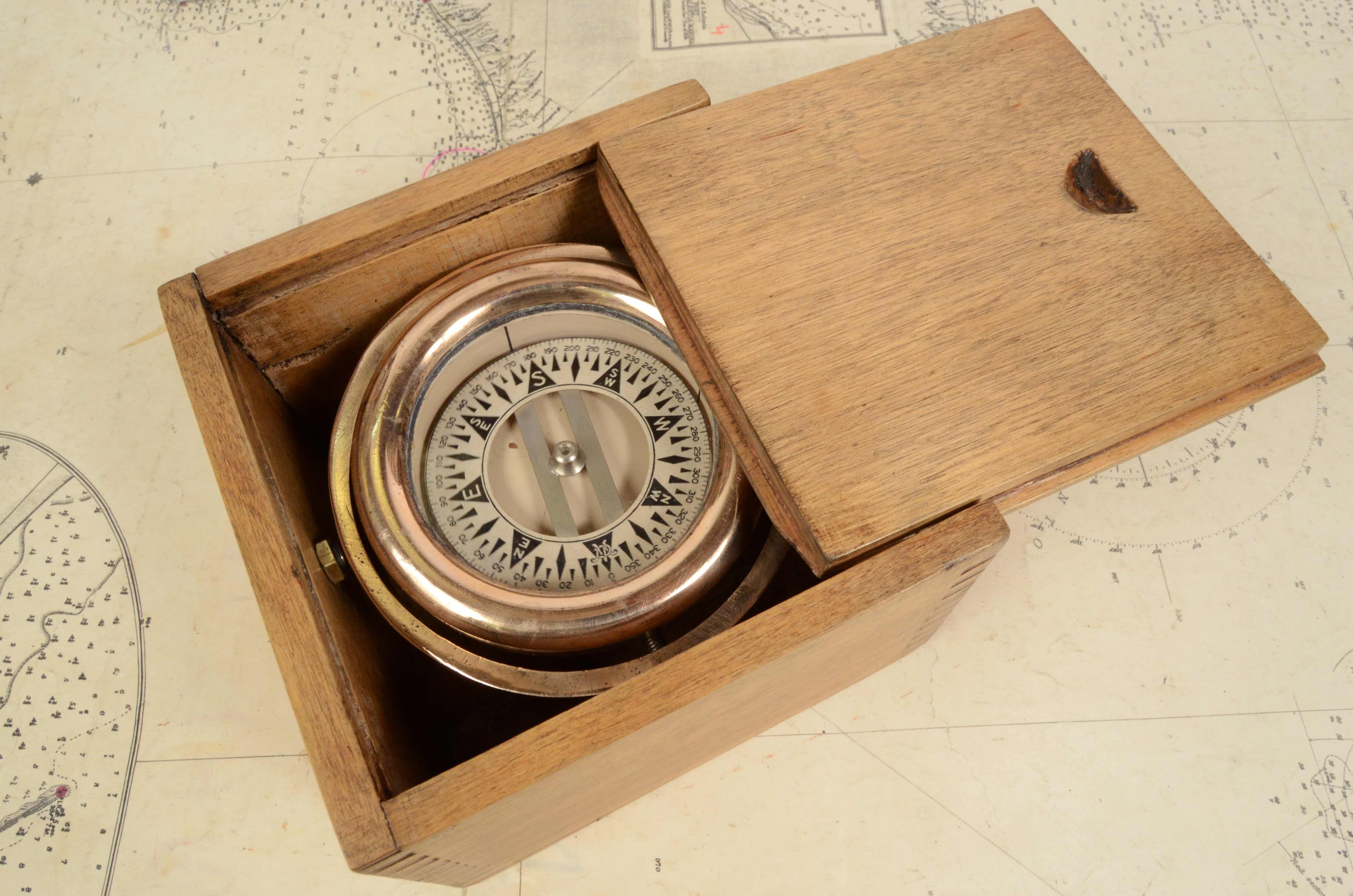 Nautical compass on cardan joint and original wooden box, English manufacture from the early 1900s. Rose on paper at eight twenty. The compass consists of a cylindrical container in brass and bronze, called mortar, on the bottom of which a hard