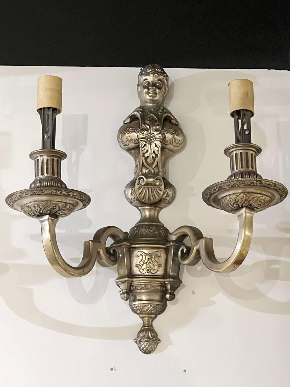 A pair of circa 1900s Caldwell Neoclassical silver plated sconces with cherub atop, two lights. Available matching chandelier  