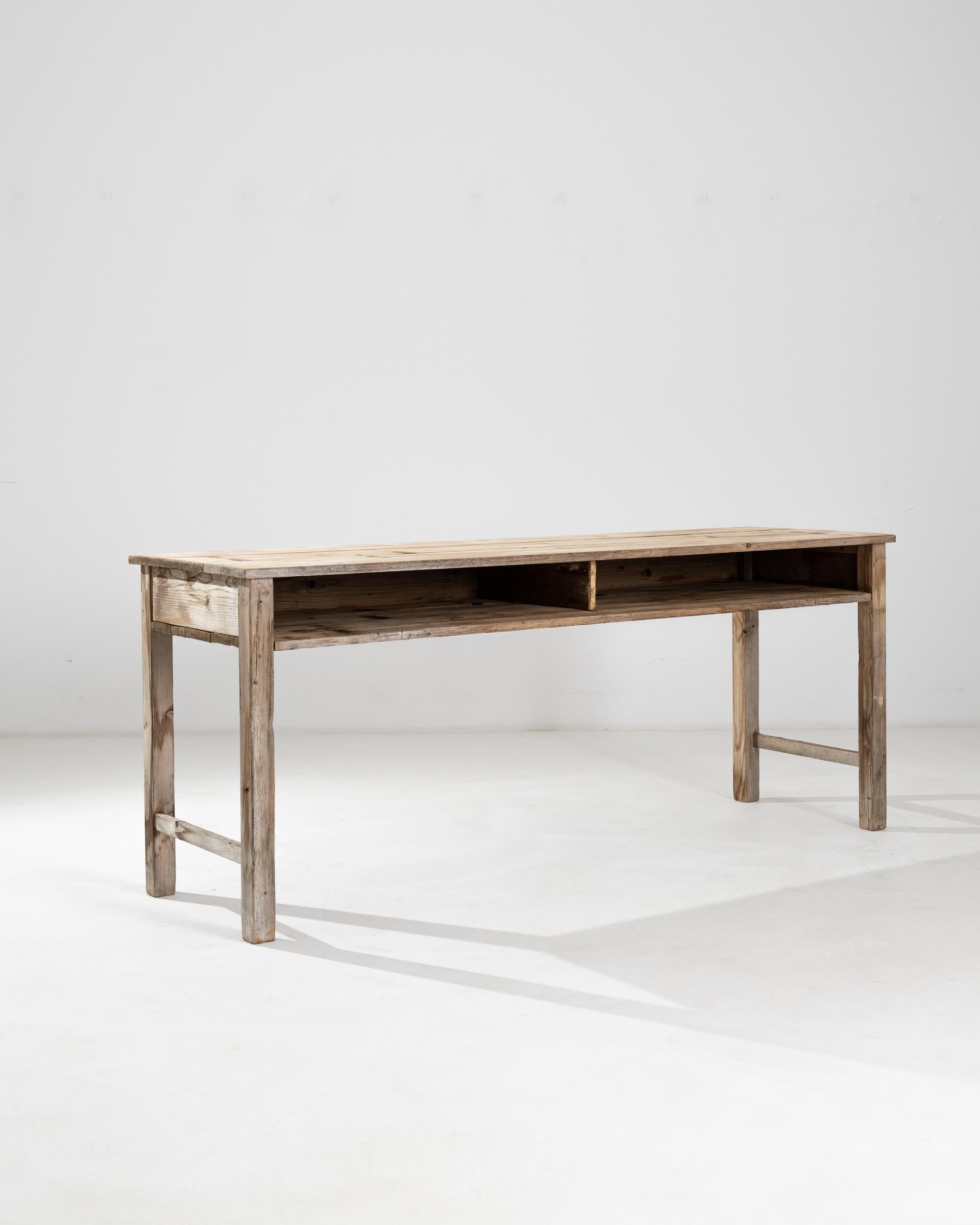 A rustic design in natural wood gives this vintage table an appealing simplicity. Made in Central Europe at the turn of the century, the form indicates that this piece was one used as a shop counter or teacher’s table —two deep niches underneath the