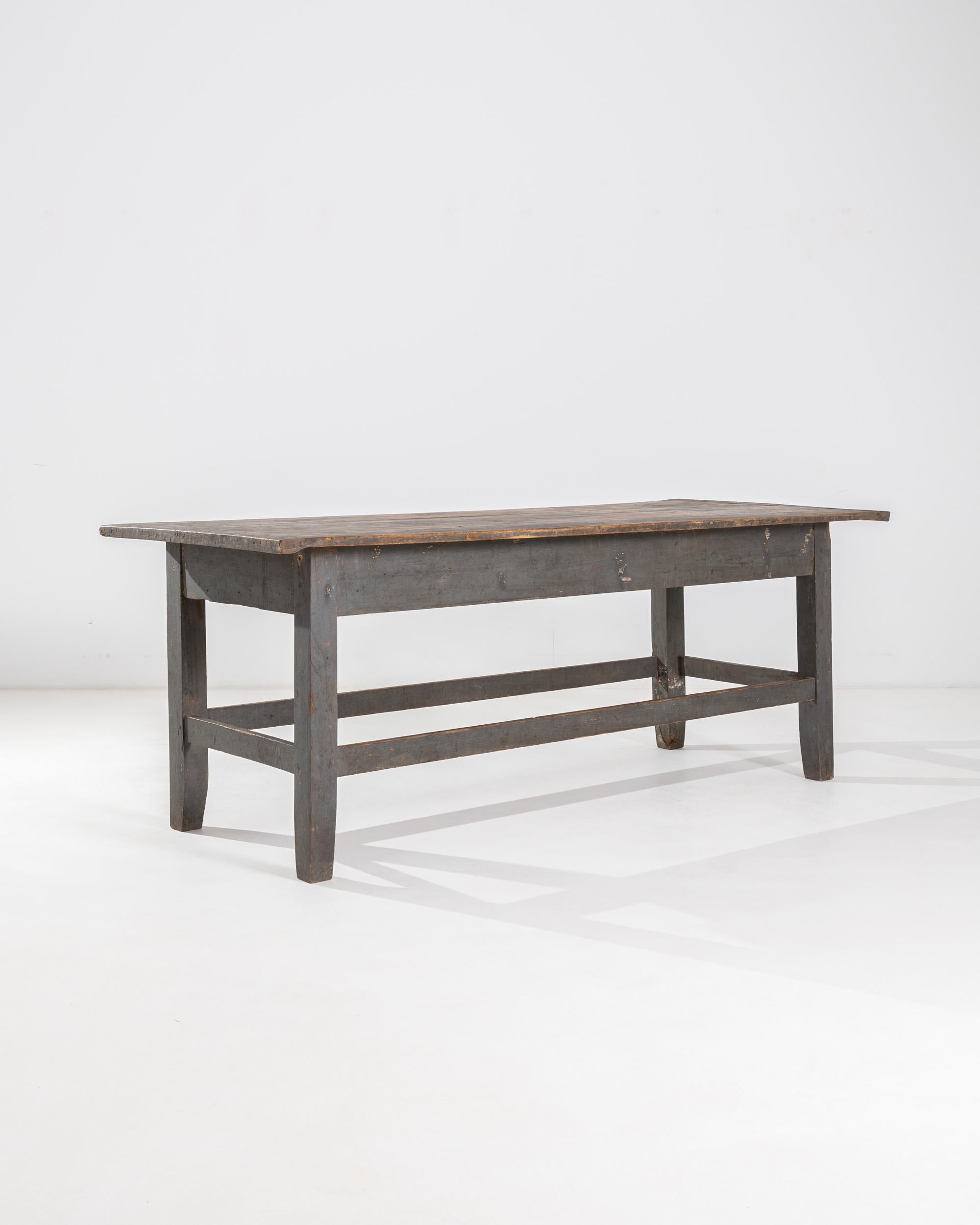 A twentieth century French wooden table. A minimal and sturdy construction characterizes this timeless Farm table. A lighter brown table top rests upon gray legs and aprons, connected by mortise and tenon joinery. A surprising and comforting array