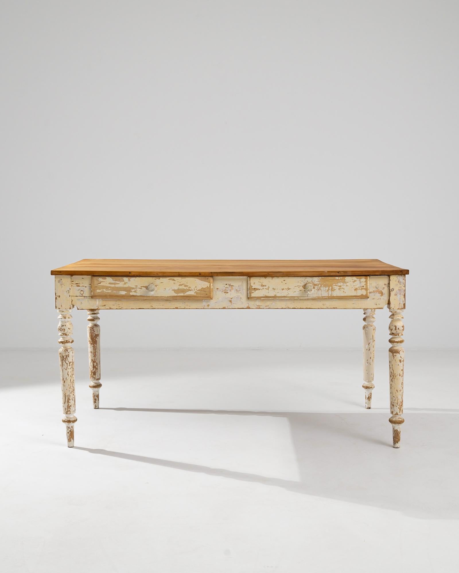 A wooden table from 1900s France. This elegantly simple table is composed of an expansive hard wood top and two sliding storage drawers. A pleasant patina has spread across its delicately lathed legs, indicating its long history. Brimming with a