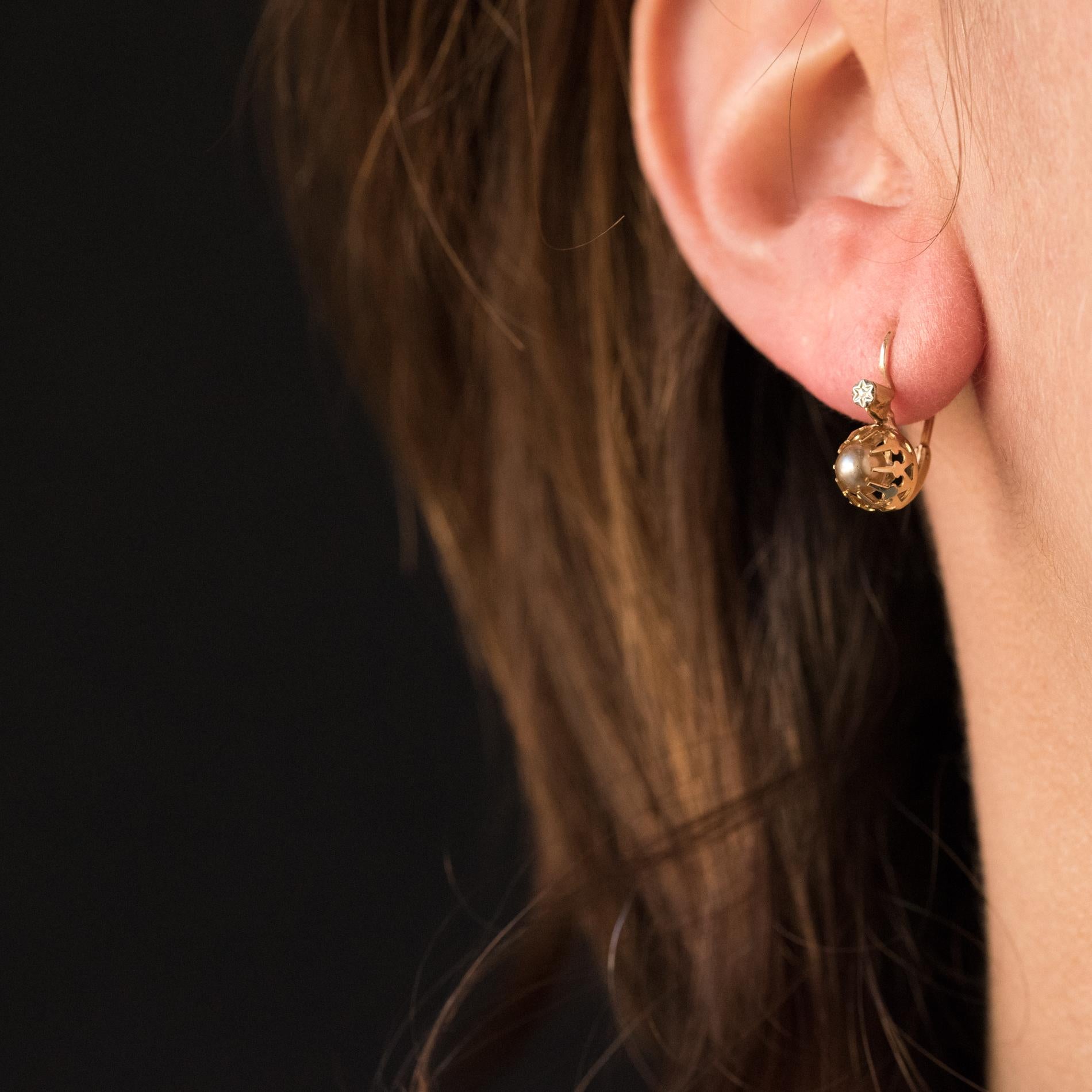 Earrings in 18 karats yellow gold, eagle's head hallmark.
Lovely sllepers earrings, they are set with claws of a cultured pearl. The claws have a lily flower pattern and are surmounted by a small engraved white gold pattern. The clasp is from the