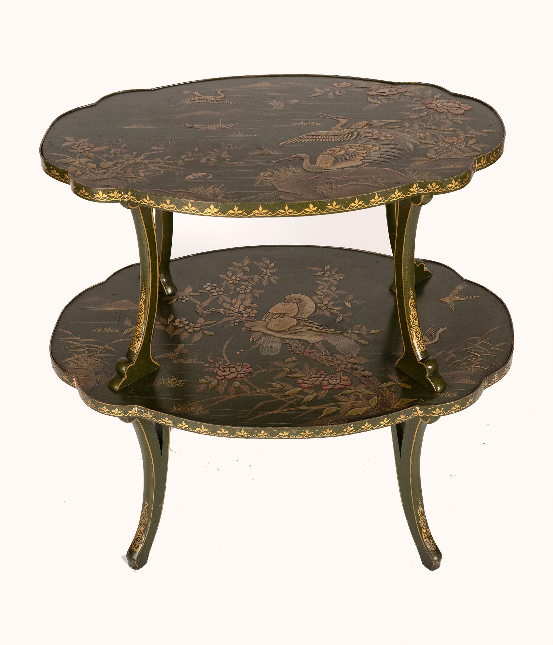 A two tiered oval side table Art Nouveau style most likely by Louis Majorelle. The oval surfaces having each surface decorated with raised Chinese inspired paintings depicting birds in a landscape the ends with scalloped edges having leaf motif