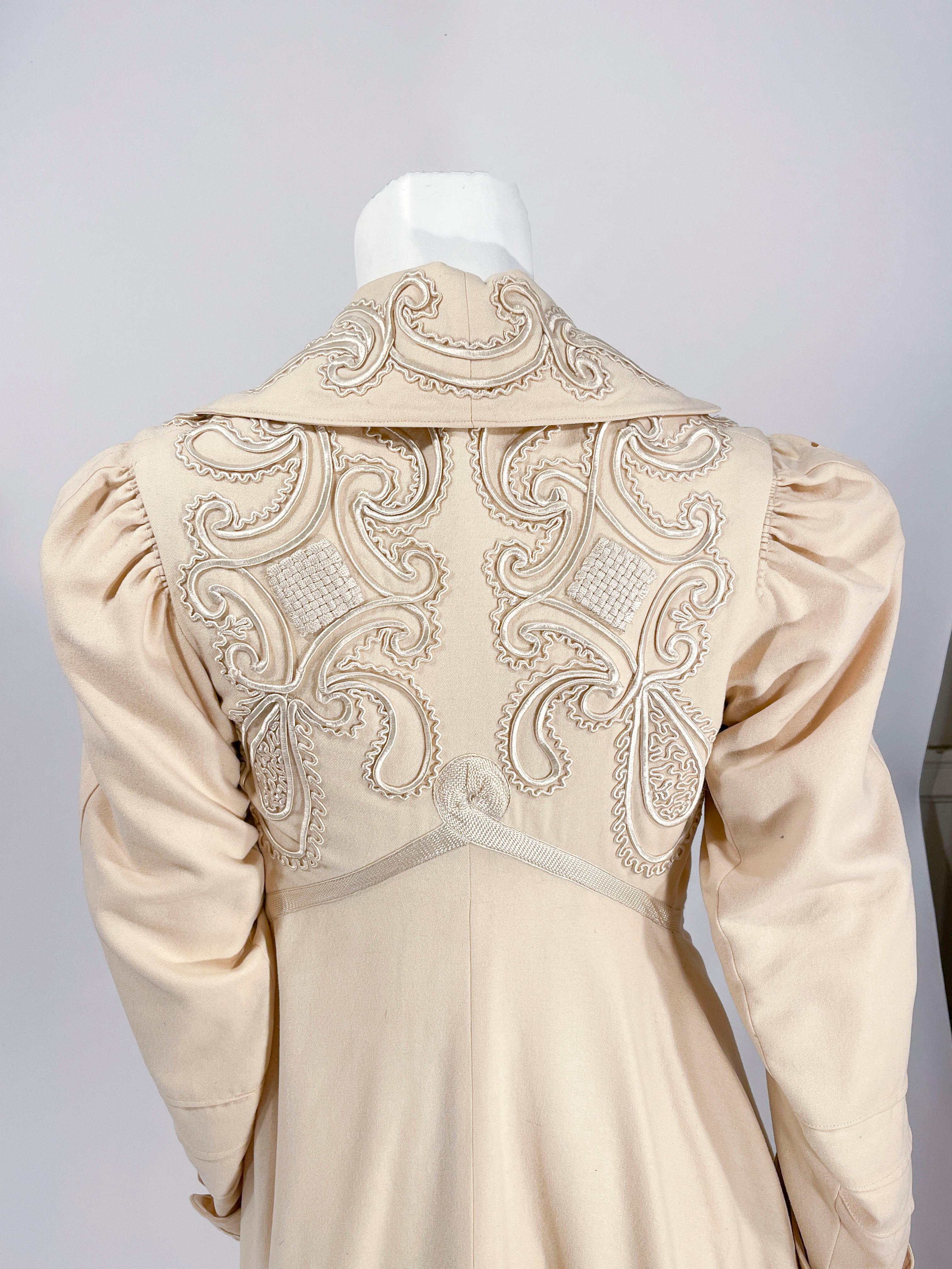 Cappotto edoardiano del 1900 in lana color crema ornato da ricami grafici in soutache di seta lungo il colletto modificato, i pannelli frontali, i polsini delle maniche e la parte superiore della schiena. Il ricamo si configura come un motivo Art