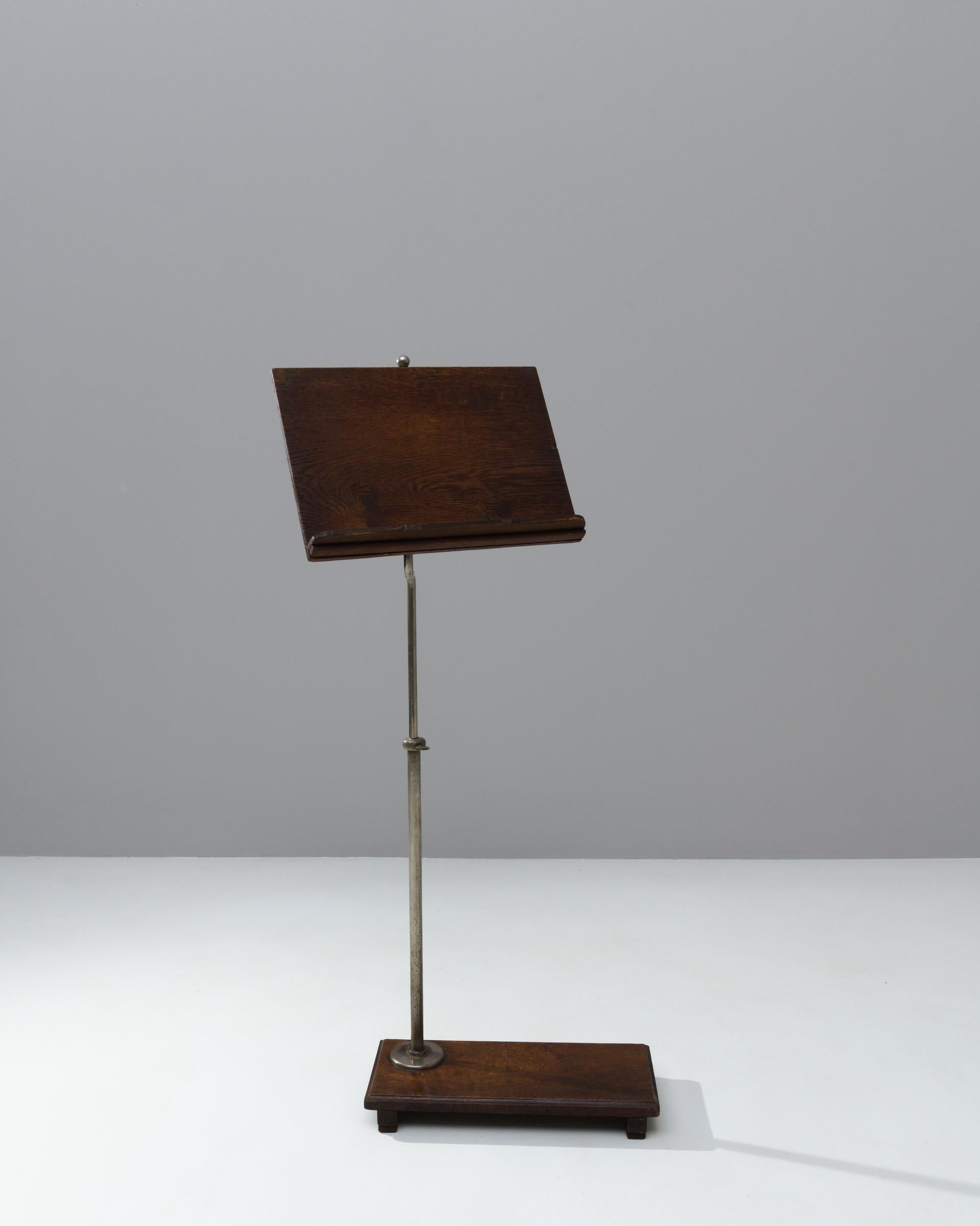 A wooden music stand made in the United Kingdom circa 1900. Sleek yet homey, this wooden and metal music stand radiates a classical beauty. With a swiveling, adjustable stand and a sturdy wooden base, this musical accessory offers both style and