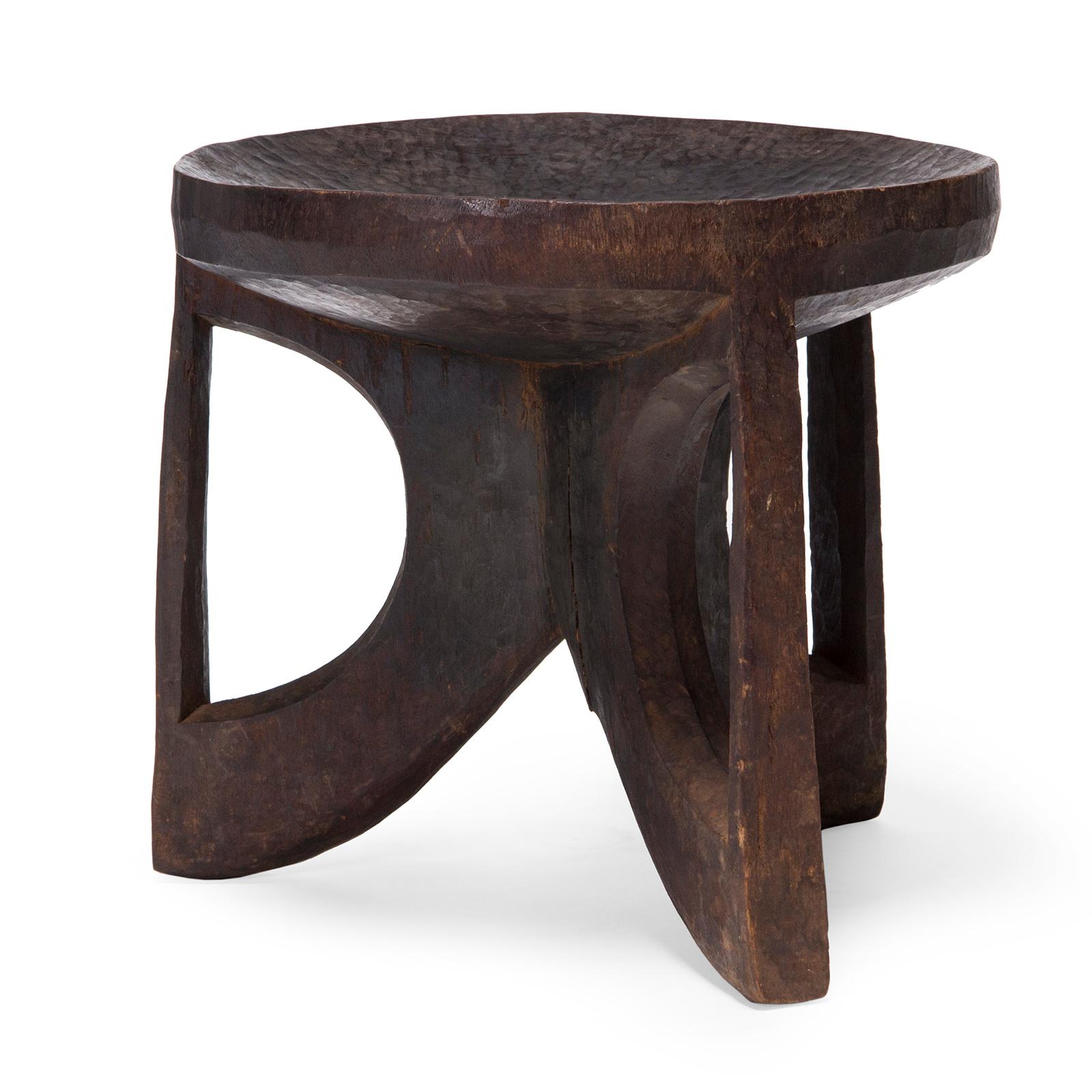 A three-legged stool carved from a single trunk of African hardwood.