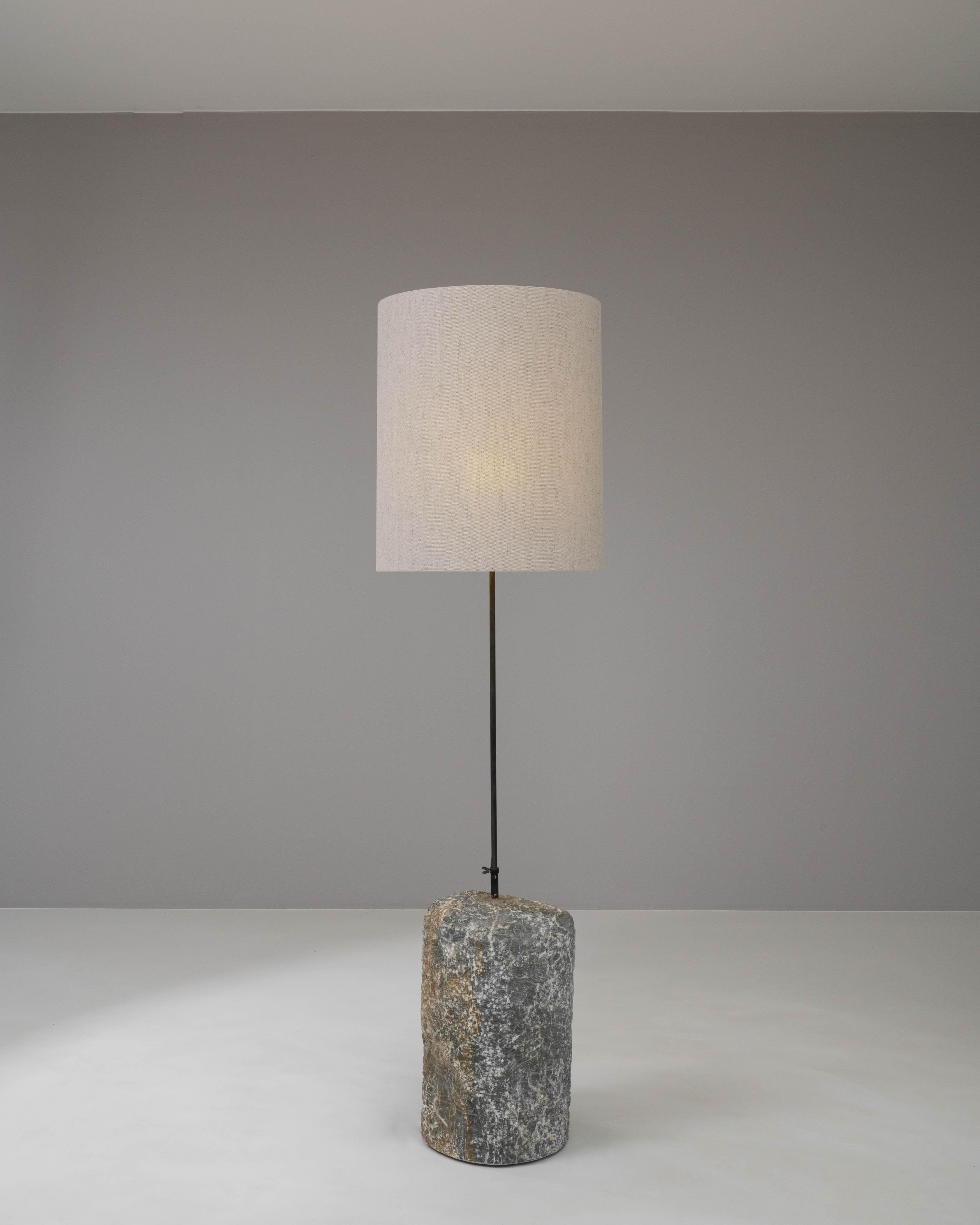 Infuse your living space with a piece of history through this 1900s European floor lamp, where the rustic charm of weathered marble meets the stark simplicity of metal. The base, hewn from a single piece of marble, boasts natural textures and a