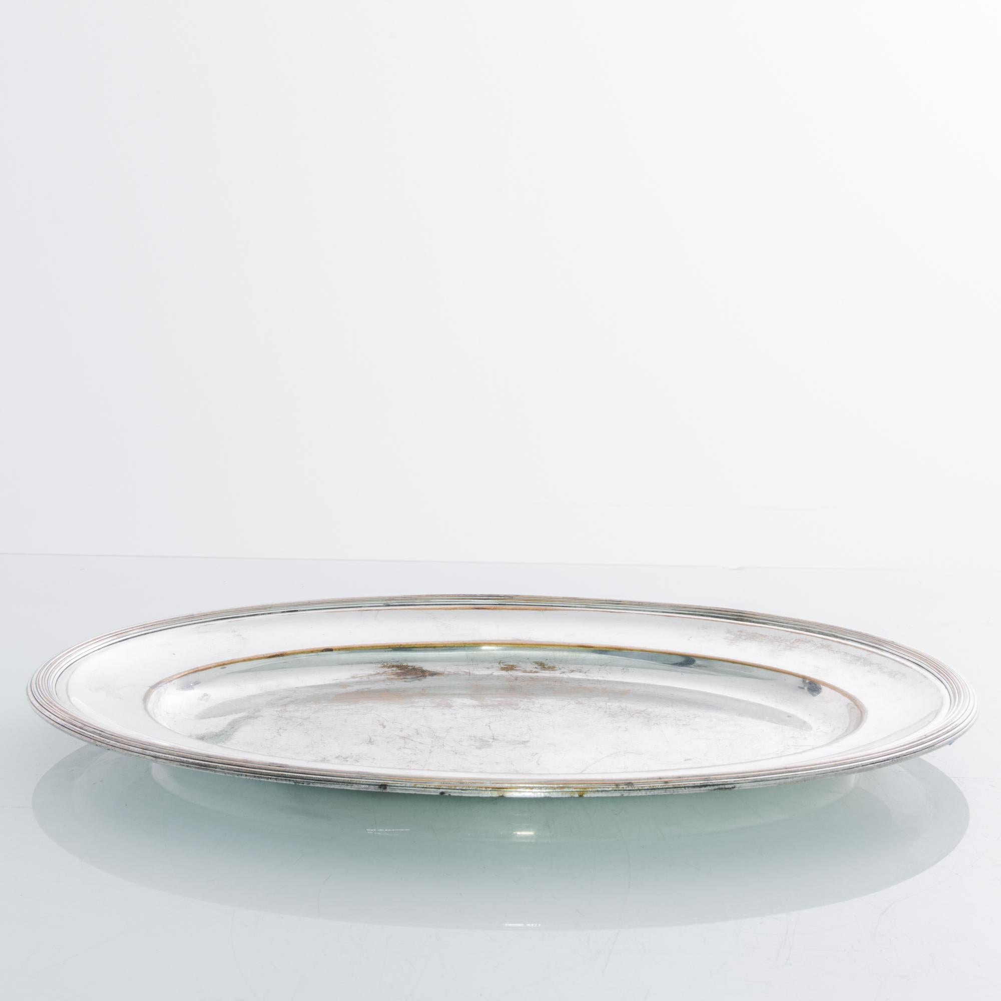 A silver plated serving tray from France, circa 1900. An elegant round shape in rich silver; a raised rim creates a natural frame for the food being served, tinted with wear to reveal the golden brass metal. This enchanting vintage piece would make