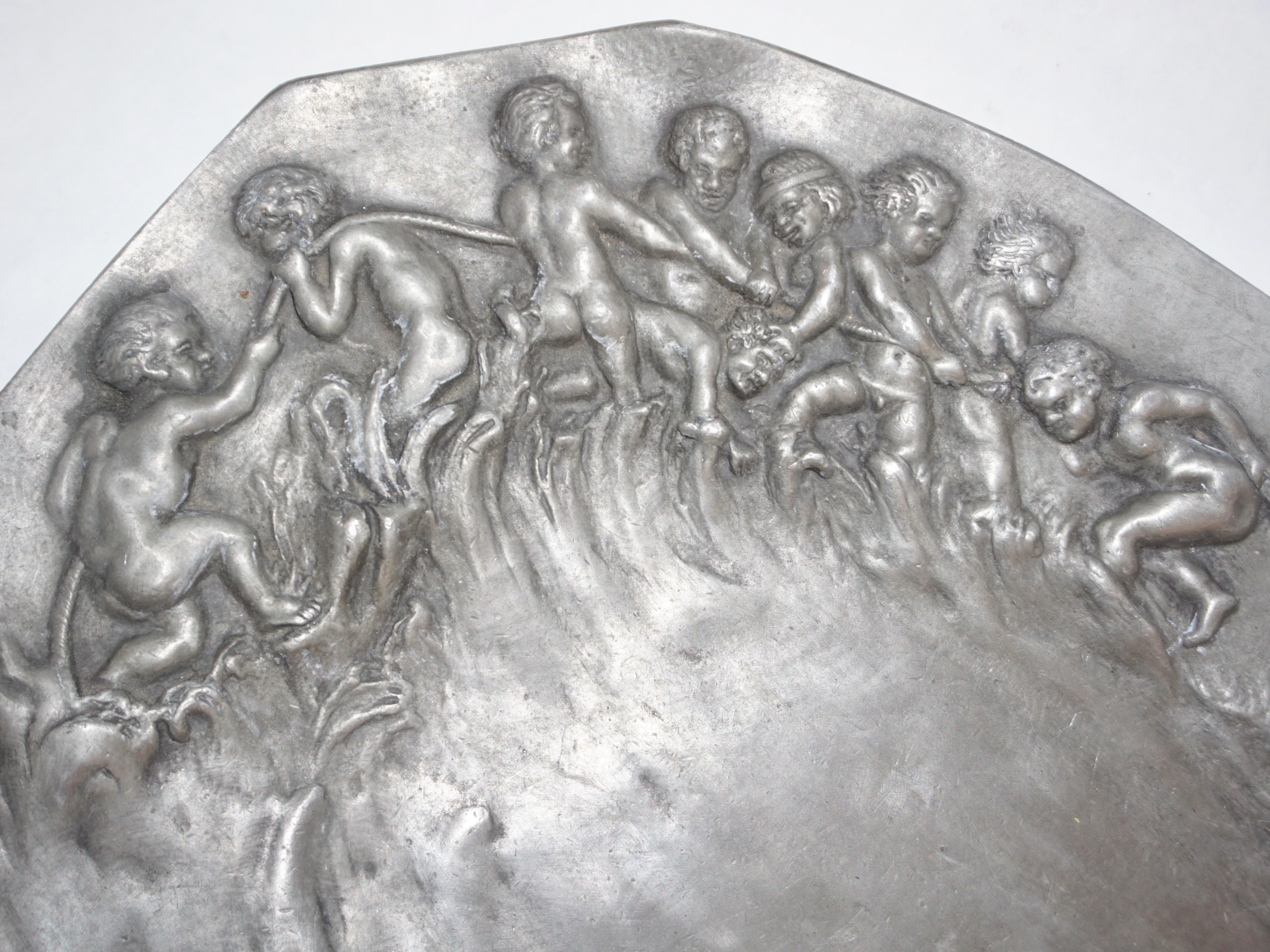 Art Nouveau handcrafted sculpted work in pewter by French artist E. Duchez circa 1900, signed piece with an interesting octagonal shape, showing a happy scene, with high quality in the details representing embossed playful putti in relief pulling a