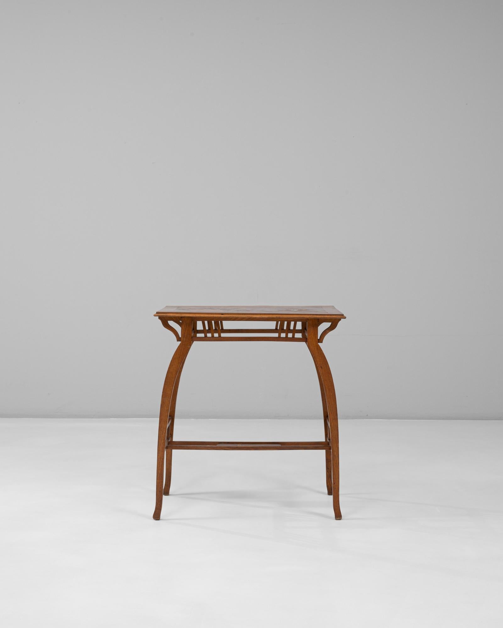 Cette table d'appoint en bois Art nouveau français des années 1900 capture la fluidité caractéristique du mouvement et l'élégance artisanale. Ses pieds légèrement arqués, reliés par des étirements en treillis, créent une base architecturale aérée, à