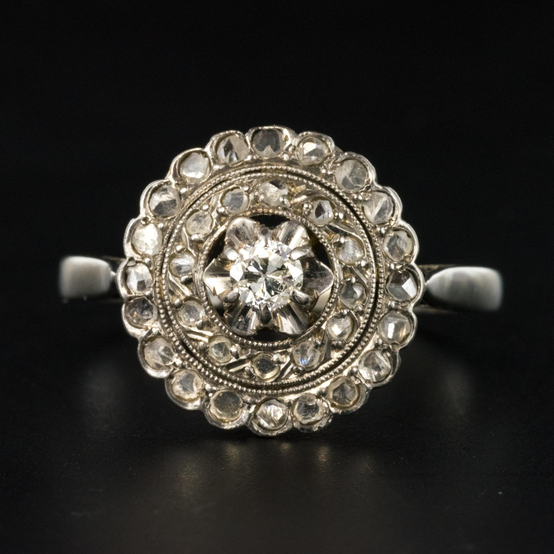 Ring in 18 karats white gold, eagle's head hallmark.
Round shape, this lovely antique ring is set with claws in the center of a double row of rose- cut diamonds of a brilliant- cut antique diamond. The basket is perforated to let light in under the